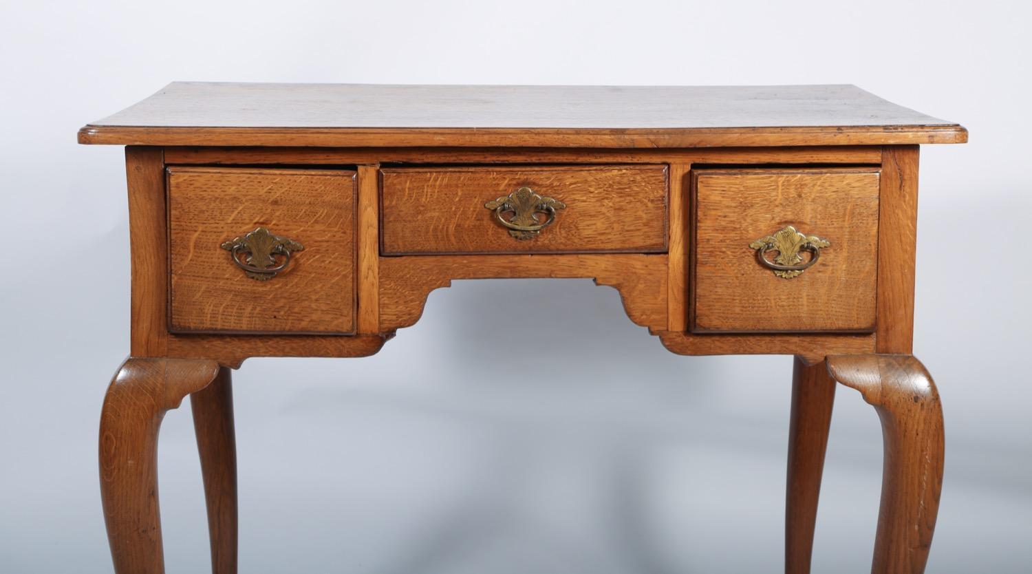 Fine 18th century oak lowboy having thumb molded top over two deep and one shallow central door, each with etched brass bail pulls, standing on graceful cabriole legs and having a nice, mellow pale color.
