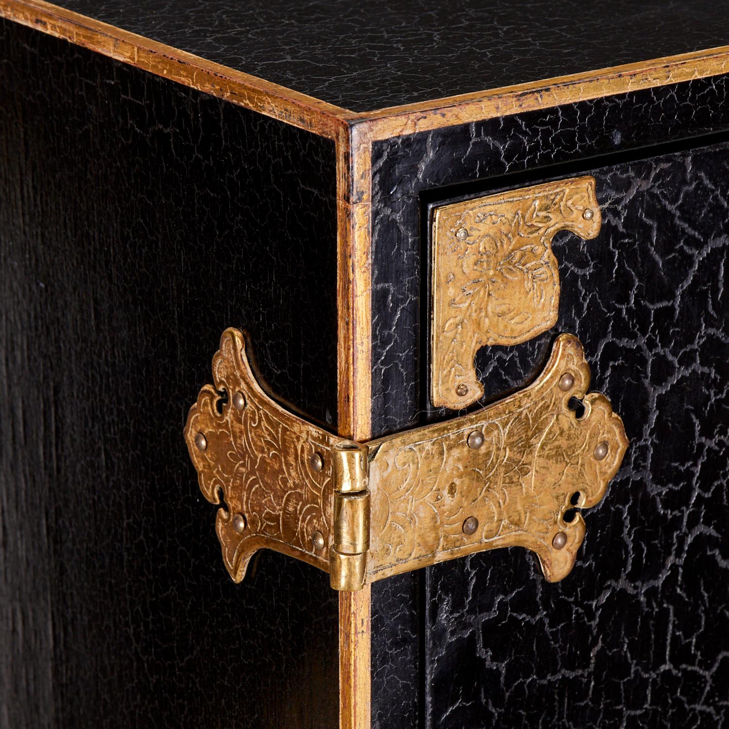 A stylish vintage 20th century, Chinoiserie style cabinet with engraved brass bracket hinges and hinged doors, opening to provision for adjustable shelving.  The black lacquer body, with an intentional craquelure finish, is decorated with gilt