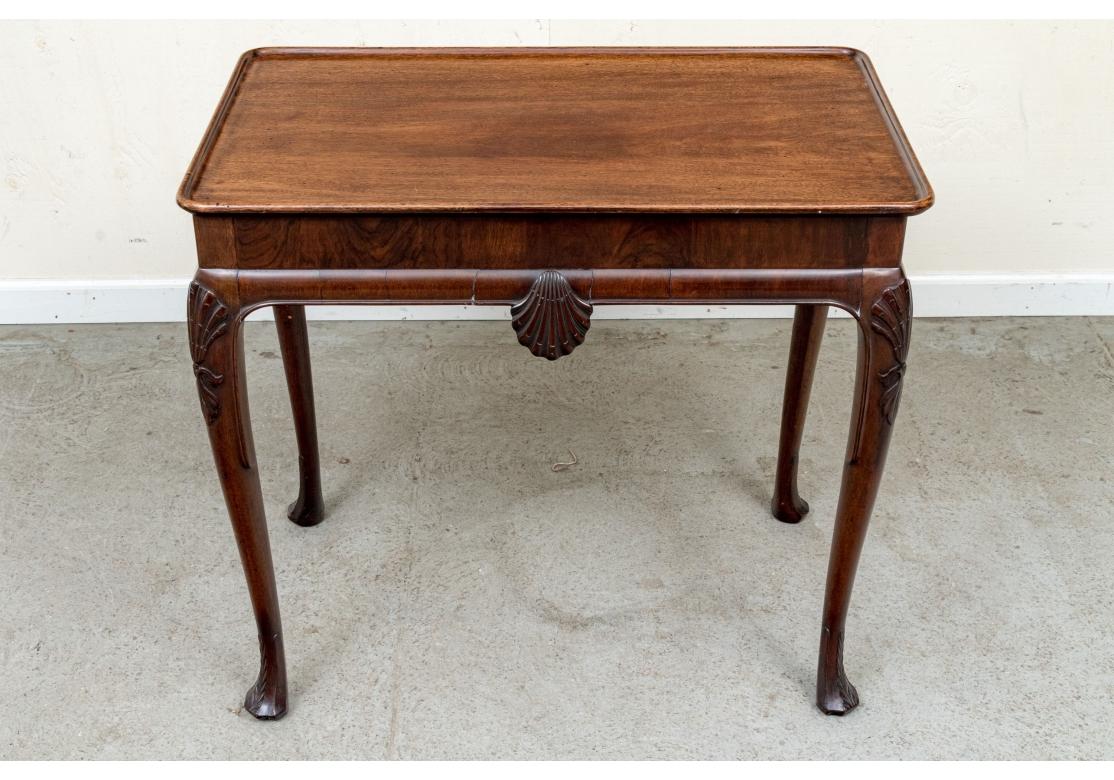 Une console très bien faite et très élégante. Console en acajou de style George I, bien veinée et de forme traditionnelle. La table a un plateau surélevé avec un bord de plateau, un tablier sculpté de coquillages surmontant les pieds Cabriolet
