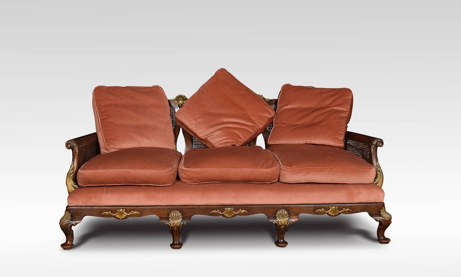 Walnut bergère three-seat sofa, the shaped back above three tracery carved vase shaped splats, splats decorated with gilded moulded decoration, flanked double cane sides and scrolling arms. The upholstered seat with removable seat and back cushions