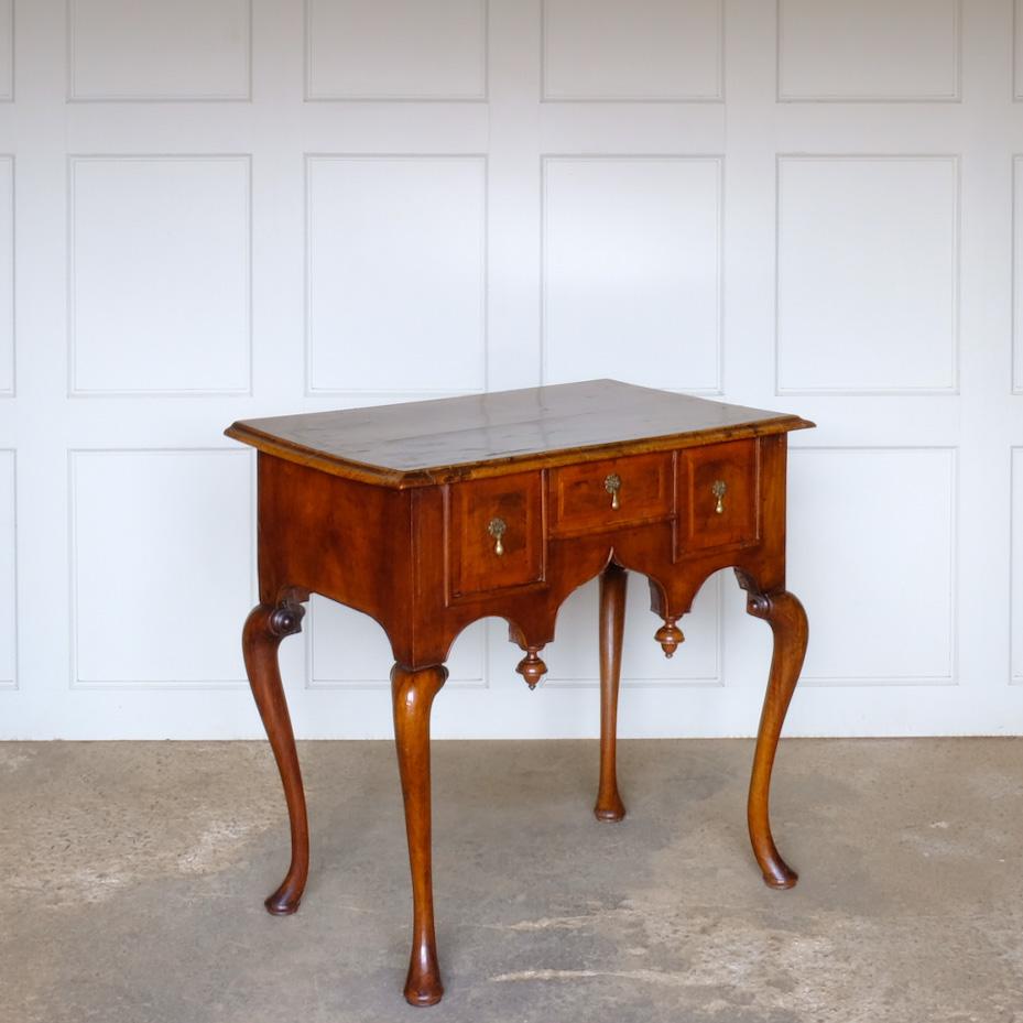 A George I walnut and feather banded side table, c. 1720. Inlaid detail to the top and a shaped apron with finials, likely added later. Evidence of old, inactive worm in places, otherwise a delightful patina commensurate with age throughout