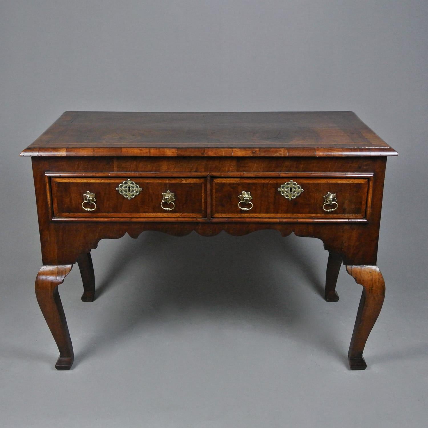 A very handsome and early Georgian figured walnut dressing table on cabriole legs with three featherbanded frieze drawers each with twin brass drop handles with split pin fixings and which appear to be original and lovely elaborately pierced