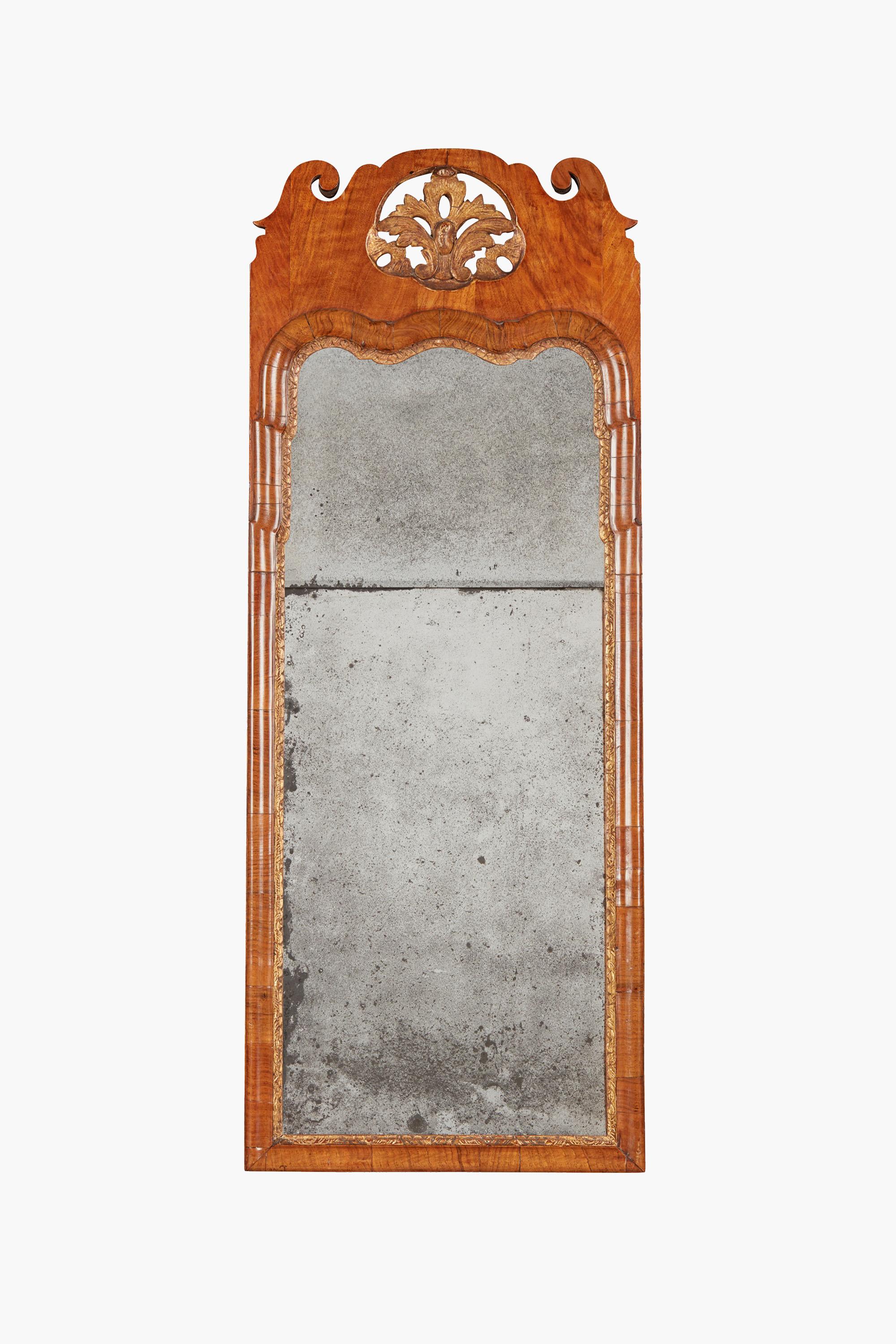 George I walnut and Parcel-gilt mirror, early 18th century

The divided mirror plate in a moulded frame with a gilt slip and pierced and scroll carved cresting.

Dimensions: 106 x 41 cm
In lovely original condition. The mirror plate is original