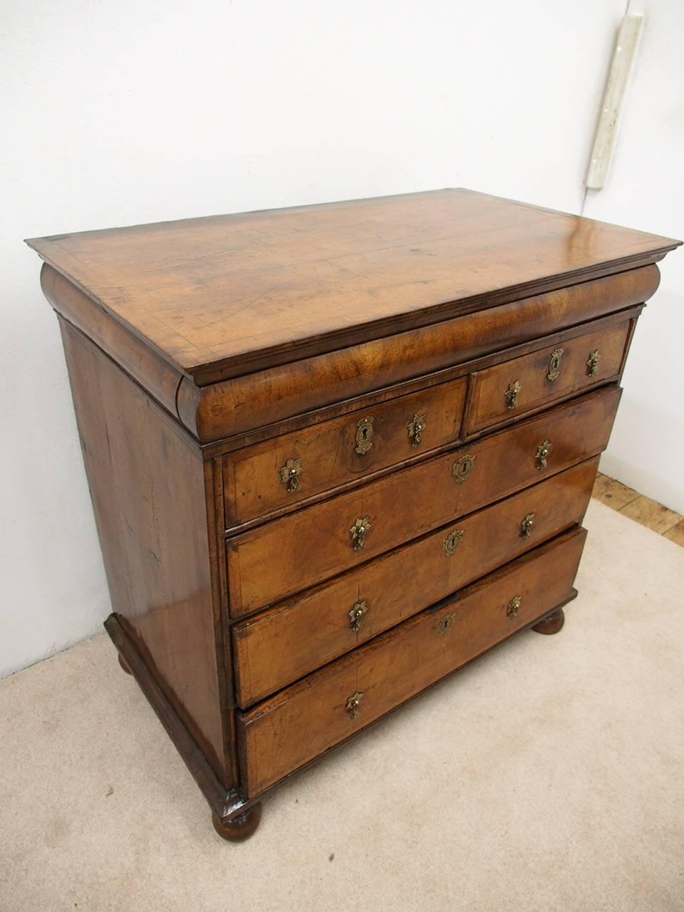 George I walnut chest of drawers with crossbanded top and sides, circa 1720. The rectangular top sits above a shaped moulding and deep cushion frieze with a long hidden drawer in front. Above two short and three long drawers with lovely herringbone
