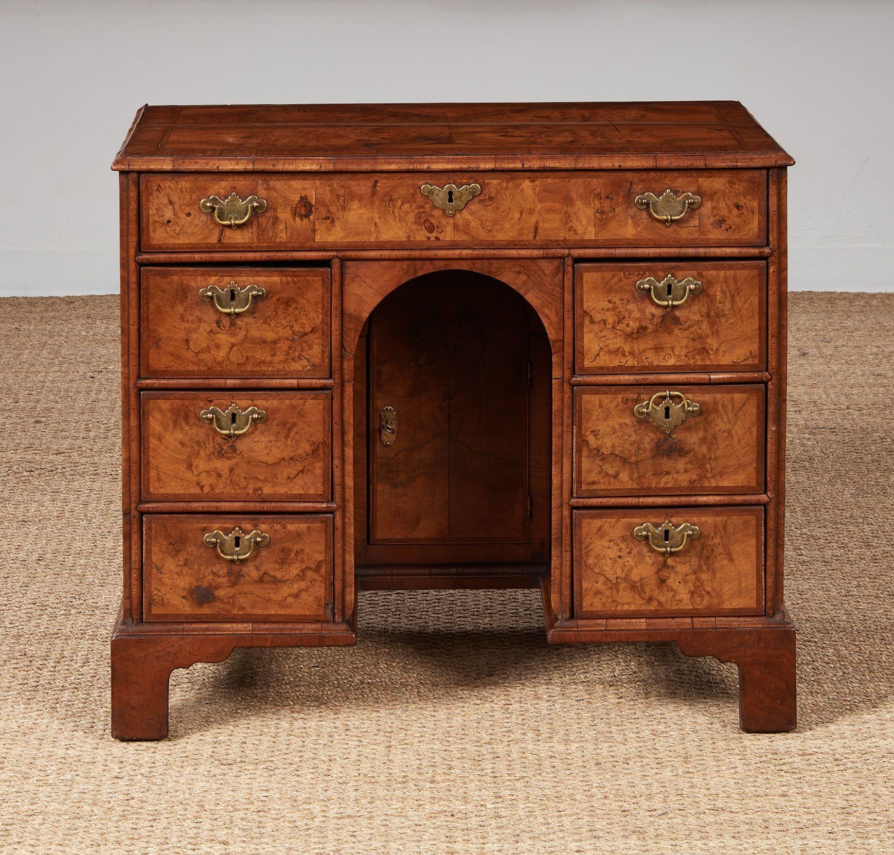 Fine early Georgian walnut kneehole desk, the top with well figured quarter veneered book-matched top having crossbanding, herringbone inlay and ogee molded edge, over similarly appointed drawers, the central knee hole having setback arched doors,