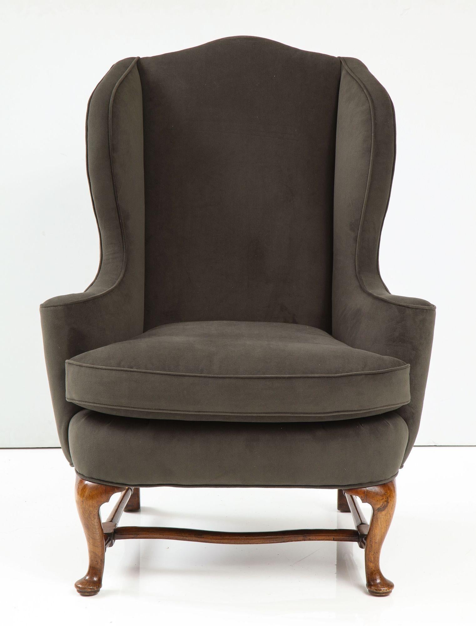 Fine George I walnut wing armchair of elegant proportions, the arched back over shaped sides and outrolled arms and standing on cabriole legs joined by turned stretchers front to back with medial shaped stretcher, possessing good rich color and
