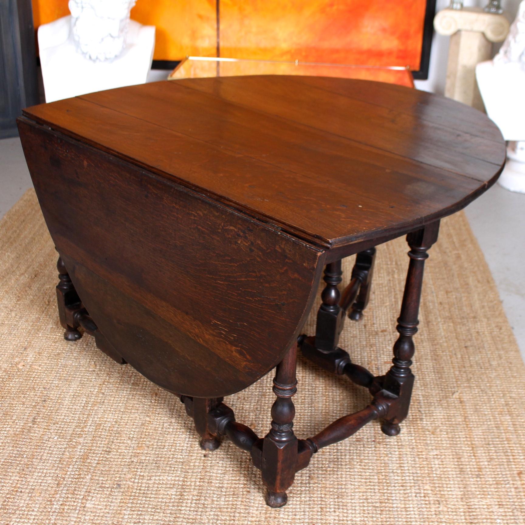 An impressive George II period oak drop-leaf gateleg dining table.

Constructed from thick cuts of solid oak boasting a well figured wild golden specked grain.

The top extending by way of drops-leafs and raised on well carved turned and fluted