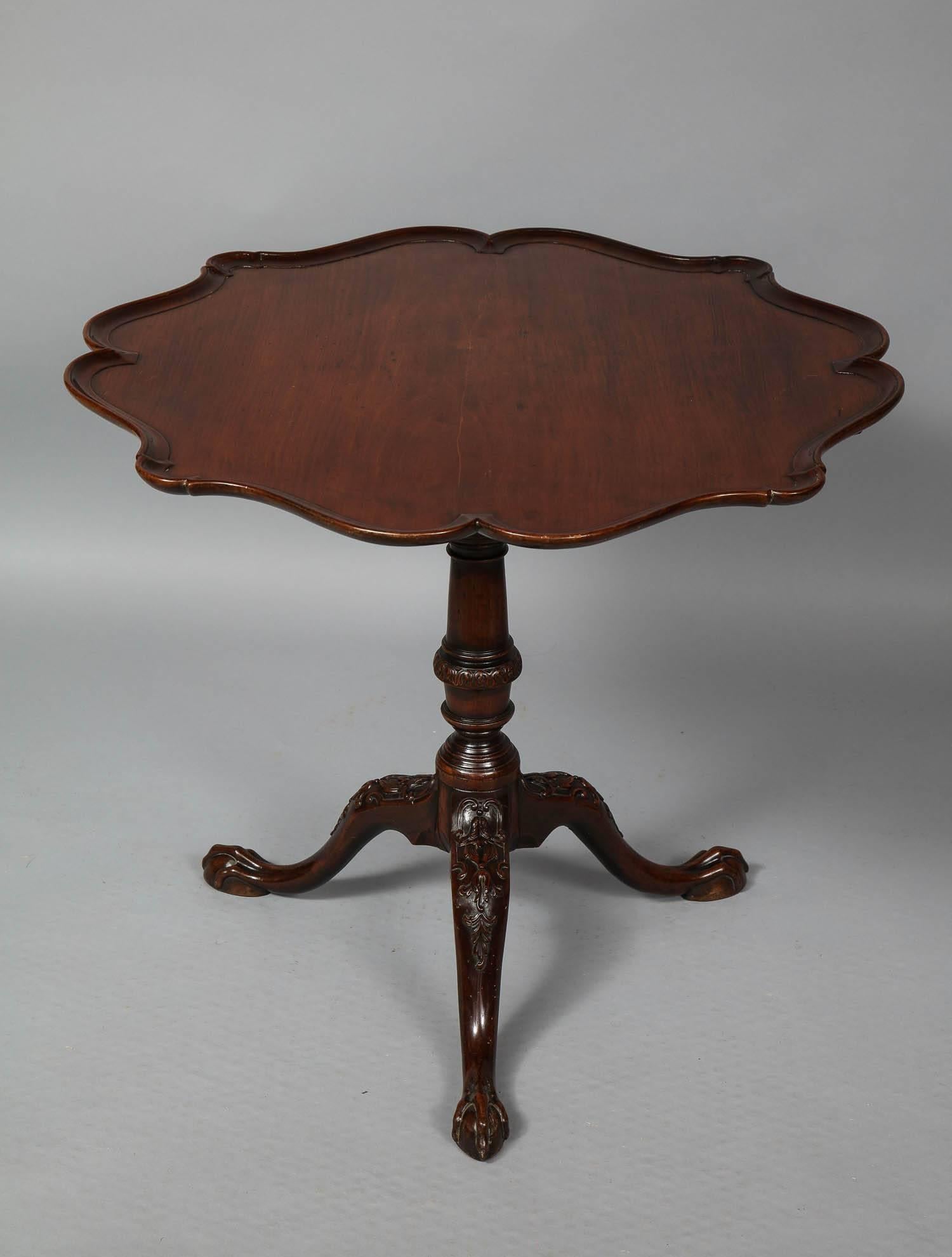 Good English 18th century tea table, the dished and lobed scalloped top fashioned from a single plank of wood, standing on turned shaft with acanthus leaf carved collar, standing on shaped feet ending in elongated ball and claw feet, unusually