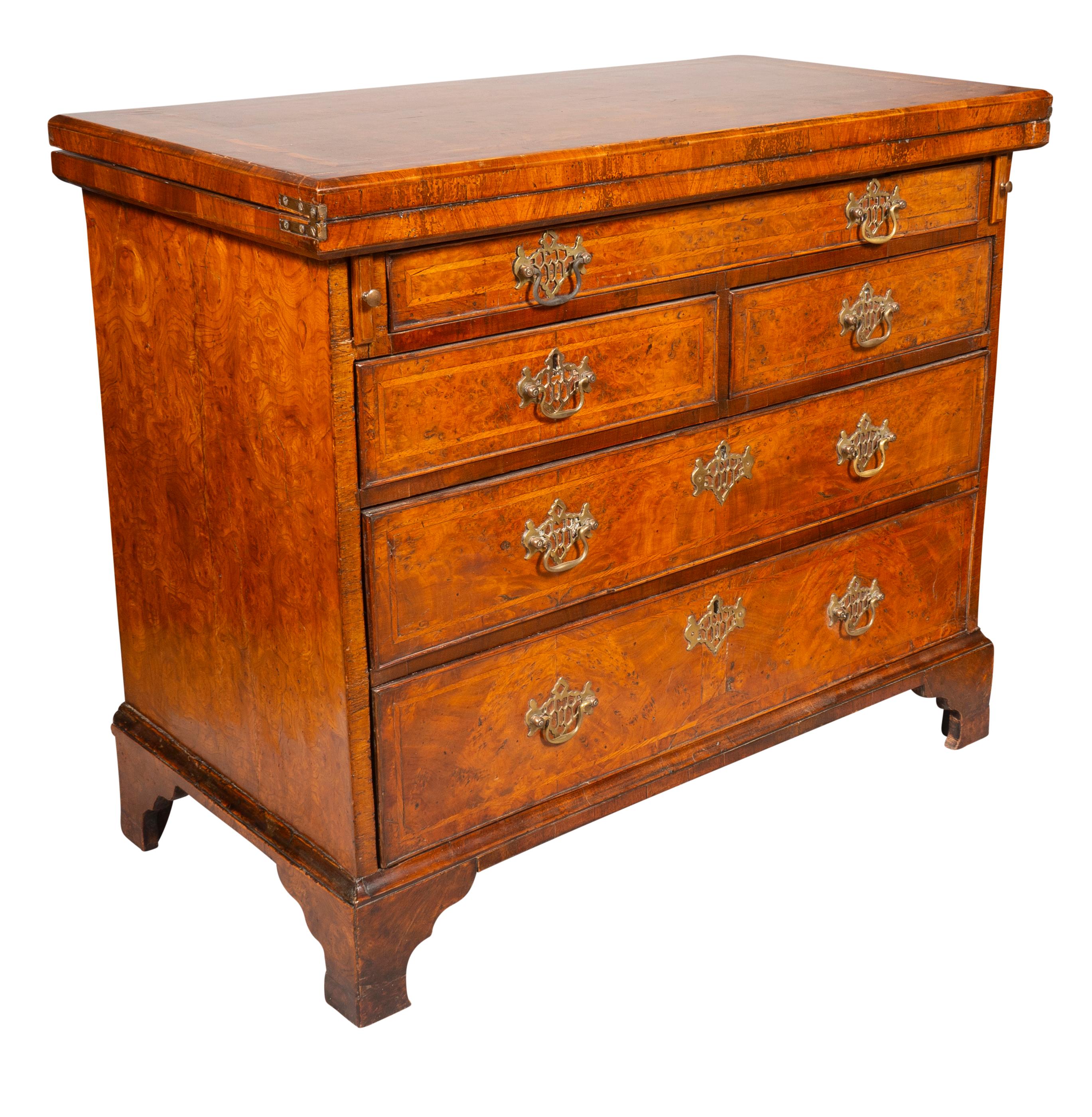 A fine piece. With a rectangular hinged top that folds forward and has two pull out supports, The interior with walnut veneers. With a long drawer over two small drawers over two long drawers. Raised on bracket feet. Pierced brass handles not