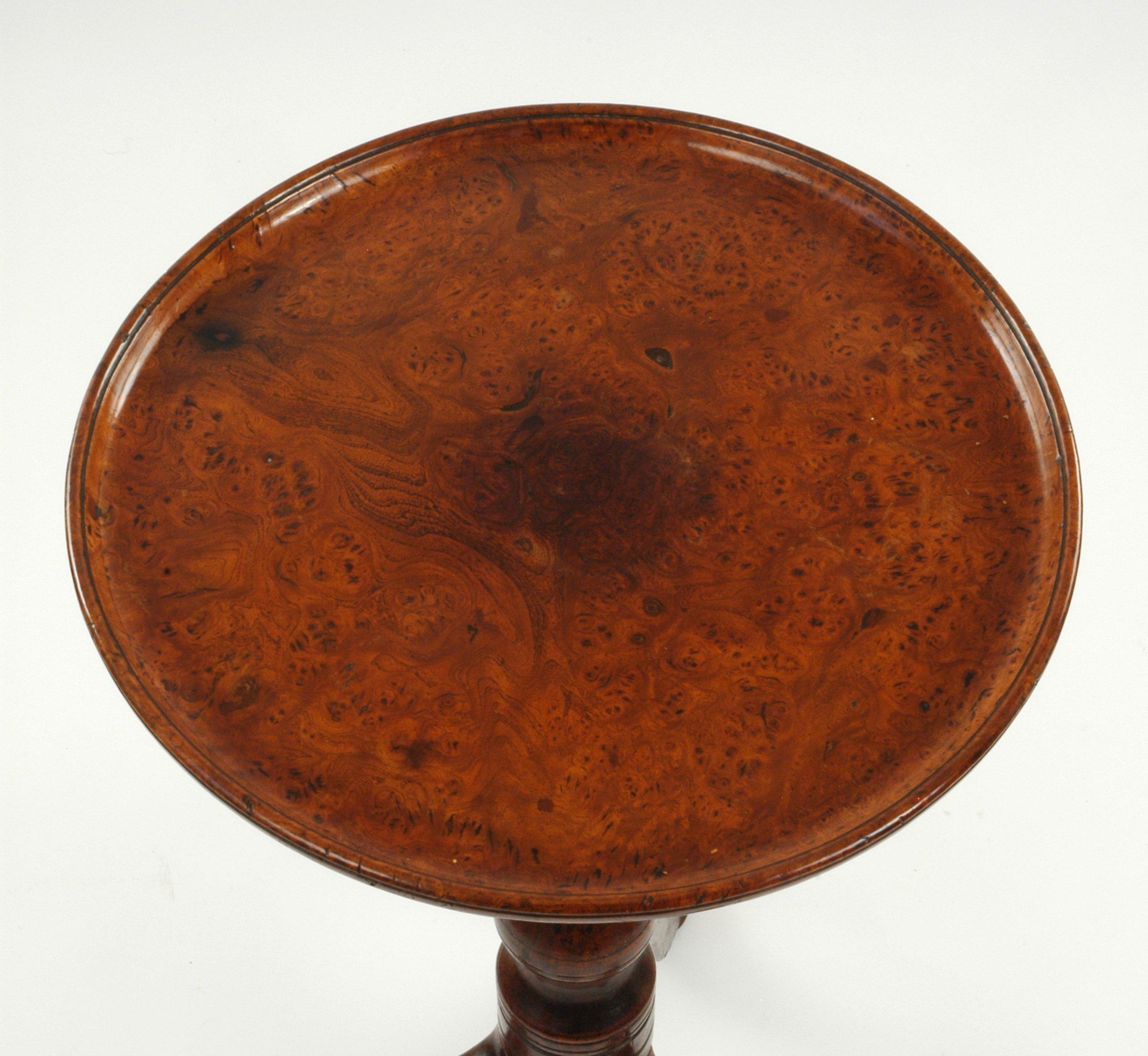 Of solid burr elm the single piece top screws to the turned walnut column on tripod legs terminating in pointed pad feet. This superb example of English country furniture has a fine rich color and is enhanced by the gently undulating top. A truly