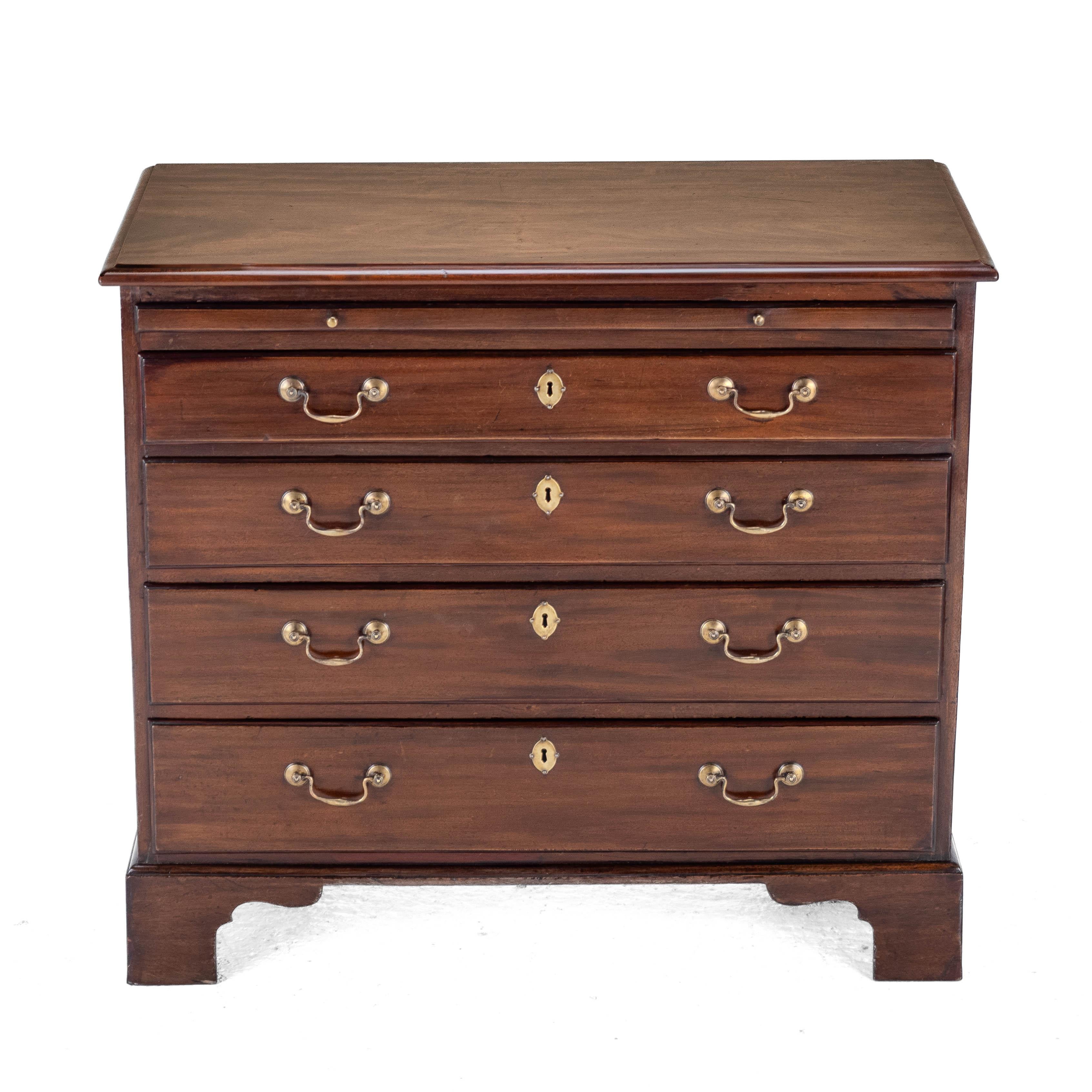Commode de célibataire en acajou d'époque George II, avec glissière de brossage en cuir, vers 1750. Cette commode aux proportions modestes est dotée d'un plateau massif de forme oblongue, joliment figuré, avec un bord mouluré. Glissière de brossage