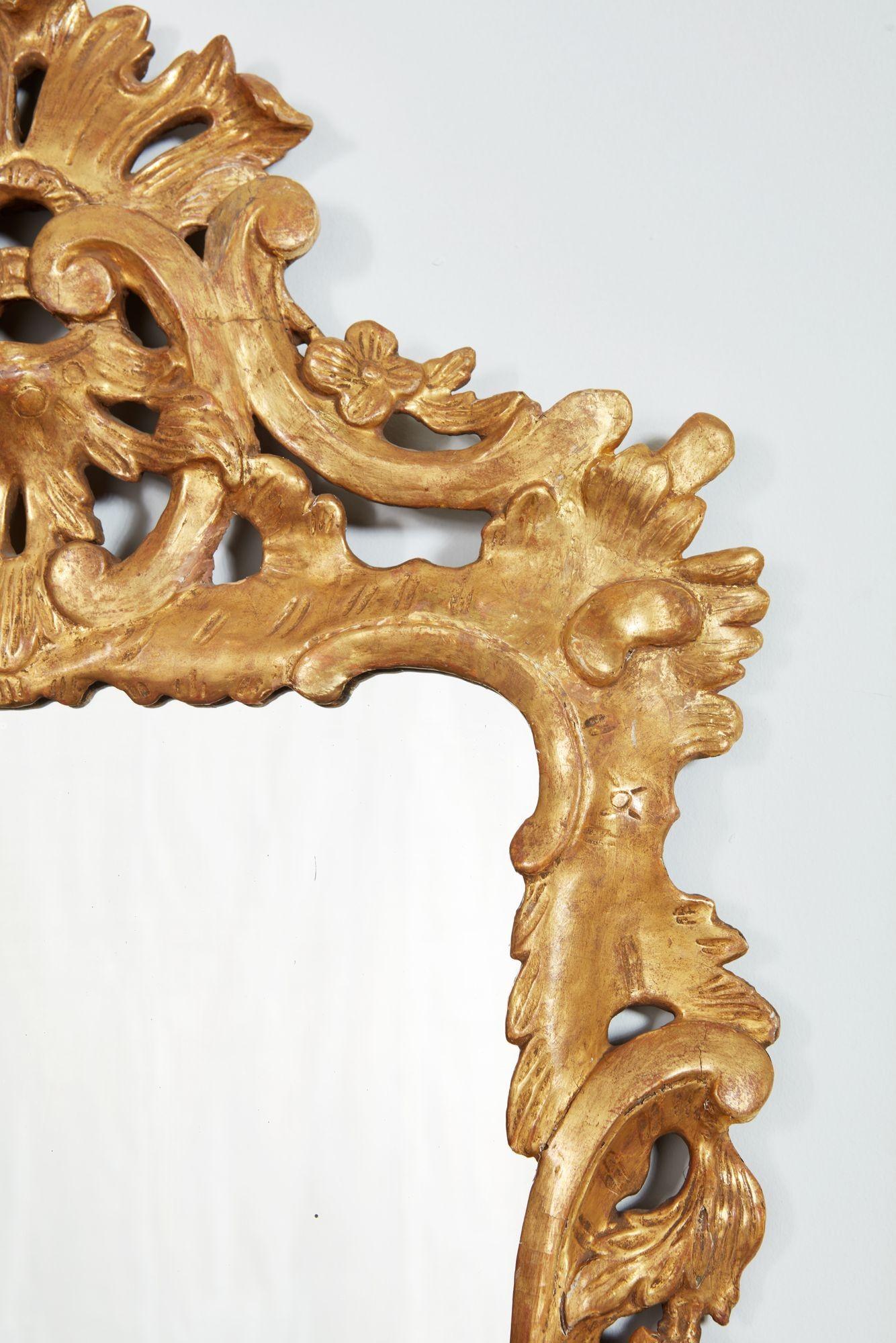 Miroir en bois doré George II avec un cadre bien sculpté en volutes et en Rocaille, avec une crête décorée d'entrelacs et un cartouche inférieur sculpté conforme. L'ensemble présente des proportions agréables. La plaque de verre au mercure est un