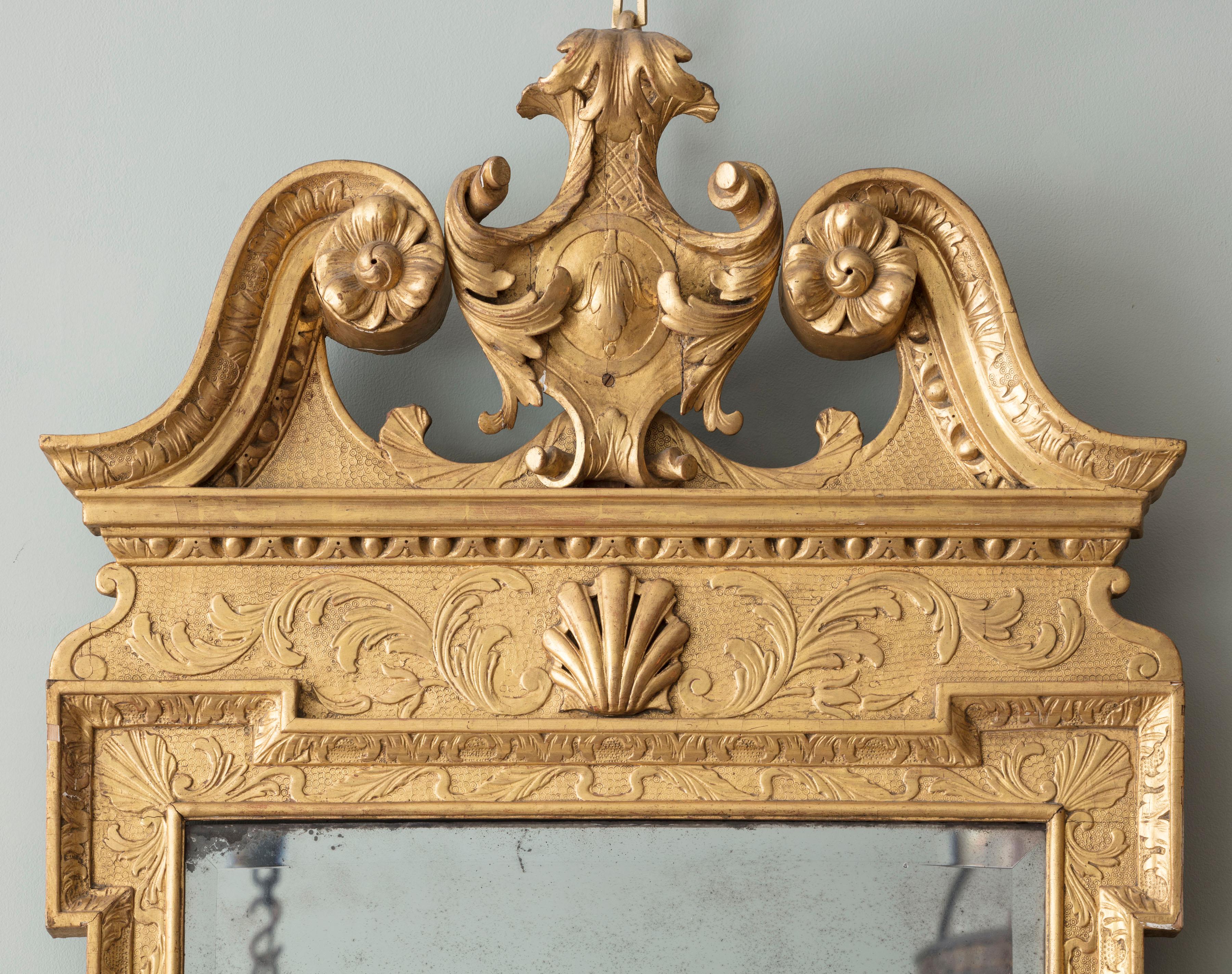 Miroir d'embarcadère en bois doré sculpté de George II, avec fronton brisé en forme de col de cygne et détails sculptés de feuillages et de coquillages. Il a conservé sa surface dorée à l'huile et sa plaque de mercure biseautée