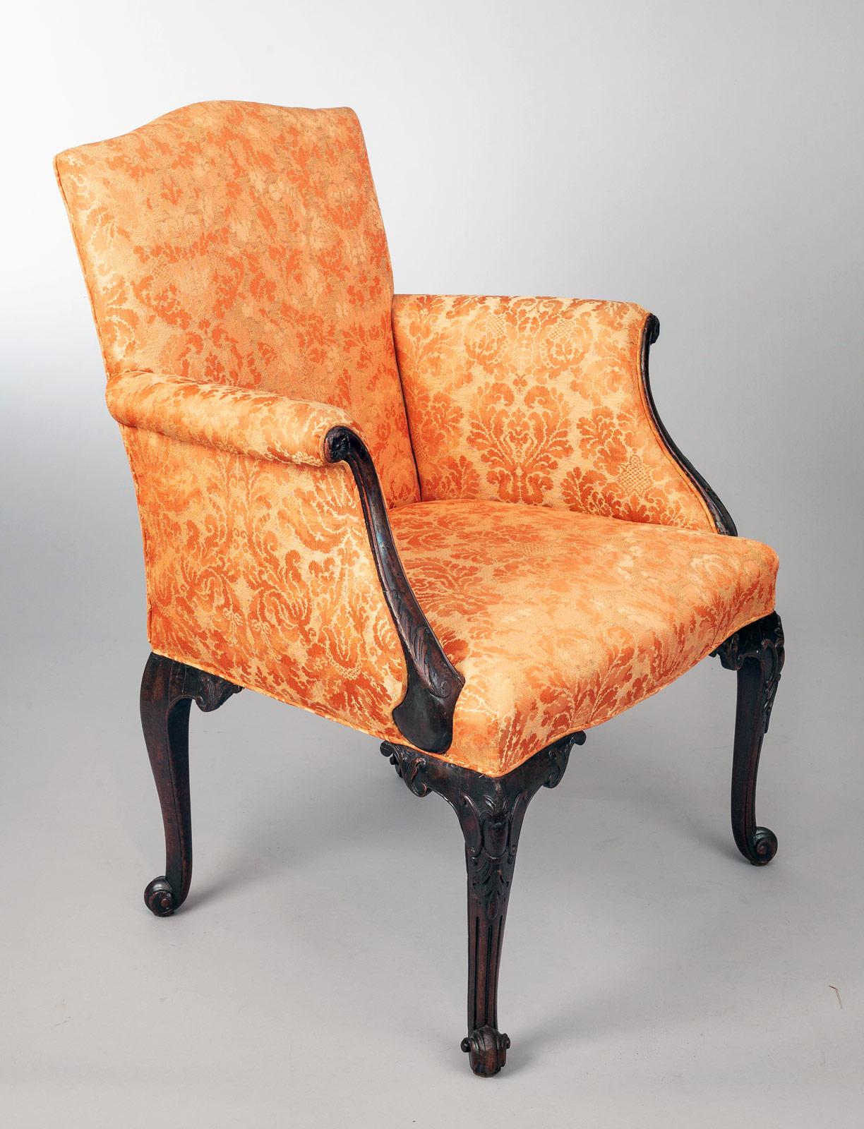 George II period bergere armchair with arched back rest, the outward scrolling arms framed by carved mahogany arm supports, above carved cabriole legs decorated with C-scrolls and a pineapple ending in a scroll foot. The back legs are also cabriole