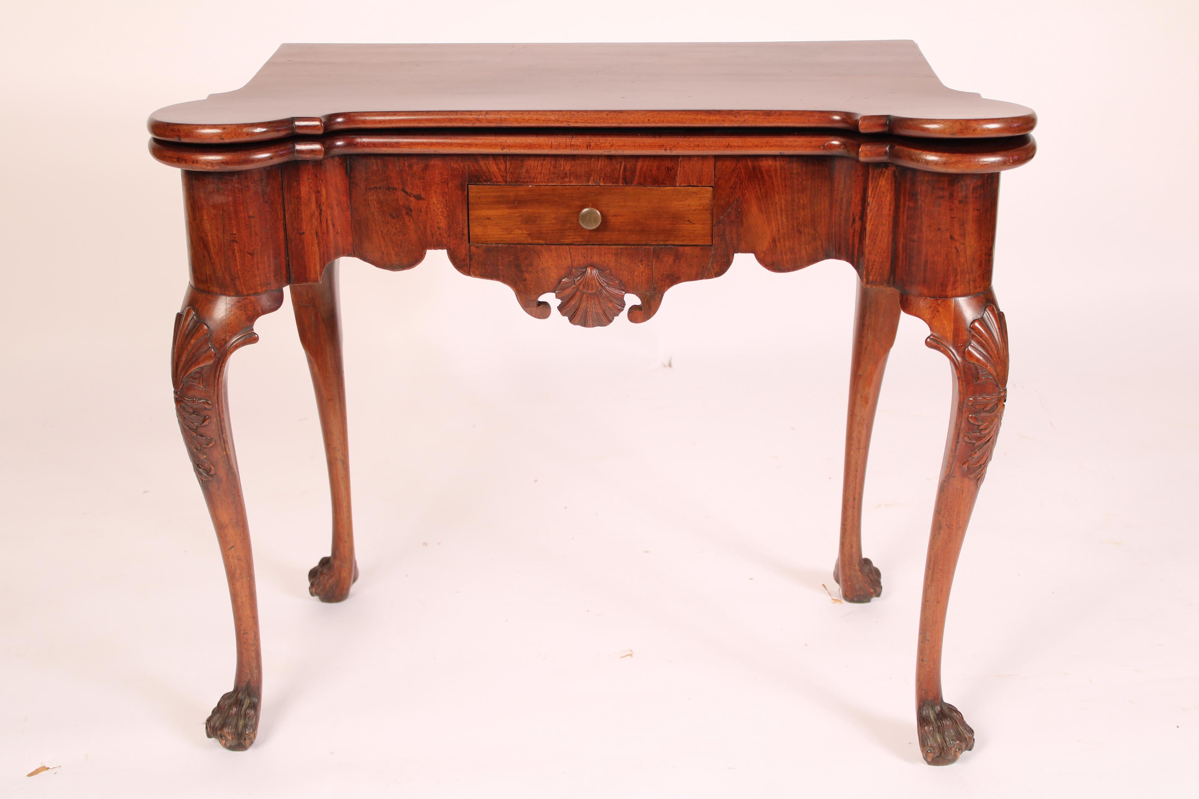 George II mahogany games table, 18th century. The single board top with turret front corners, a frieze with a central shell carving, drawer and scalloped apron, resting on 4 cabriole legs each with shell carved knees and hairy paw feet. The felt