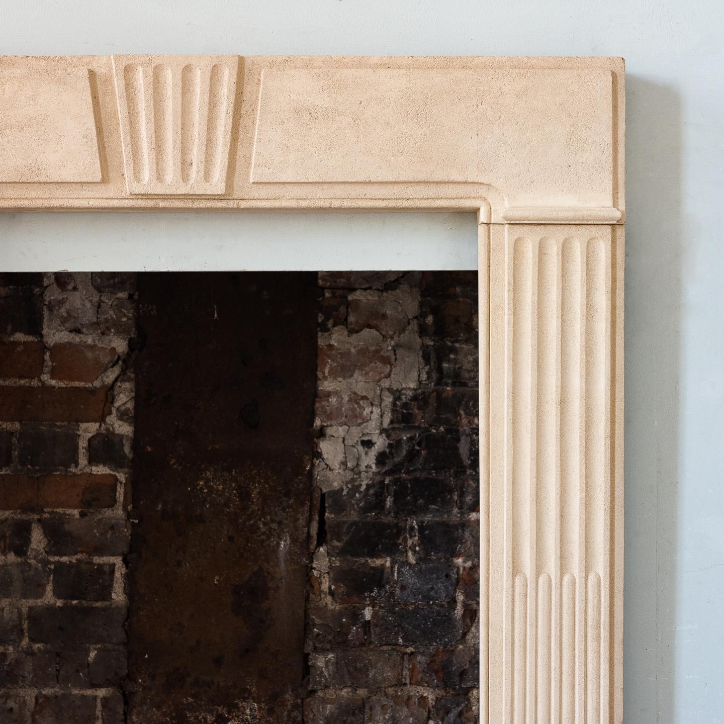 A George II Clipsham stone fire surround, of architectural form, the paneled header centred by fluted Keystone on stop-fluted jambs, on block feet.

Measures: Opening width 79.5cm x 103.5cm high.