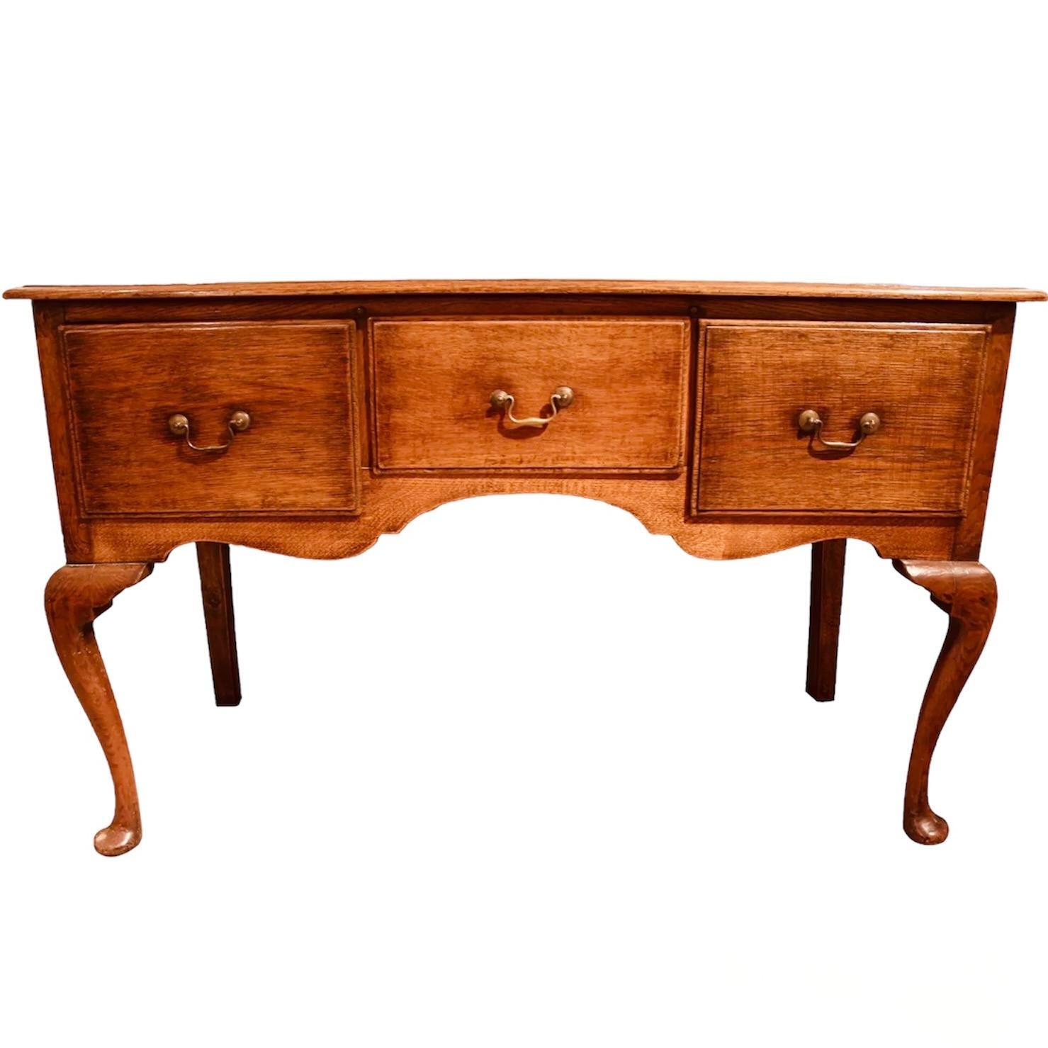 A very nicely proportioned English oak dresser base sideboard resting on cabriole legs in the front terminating in pad feet, with stile legs in the back. Three good sized drawers are fitted into the shaped front of the case. Rustic and elegant at