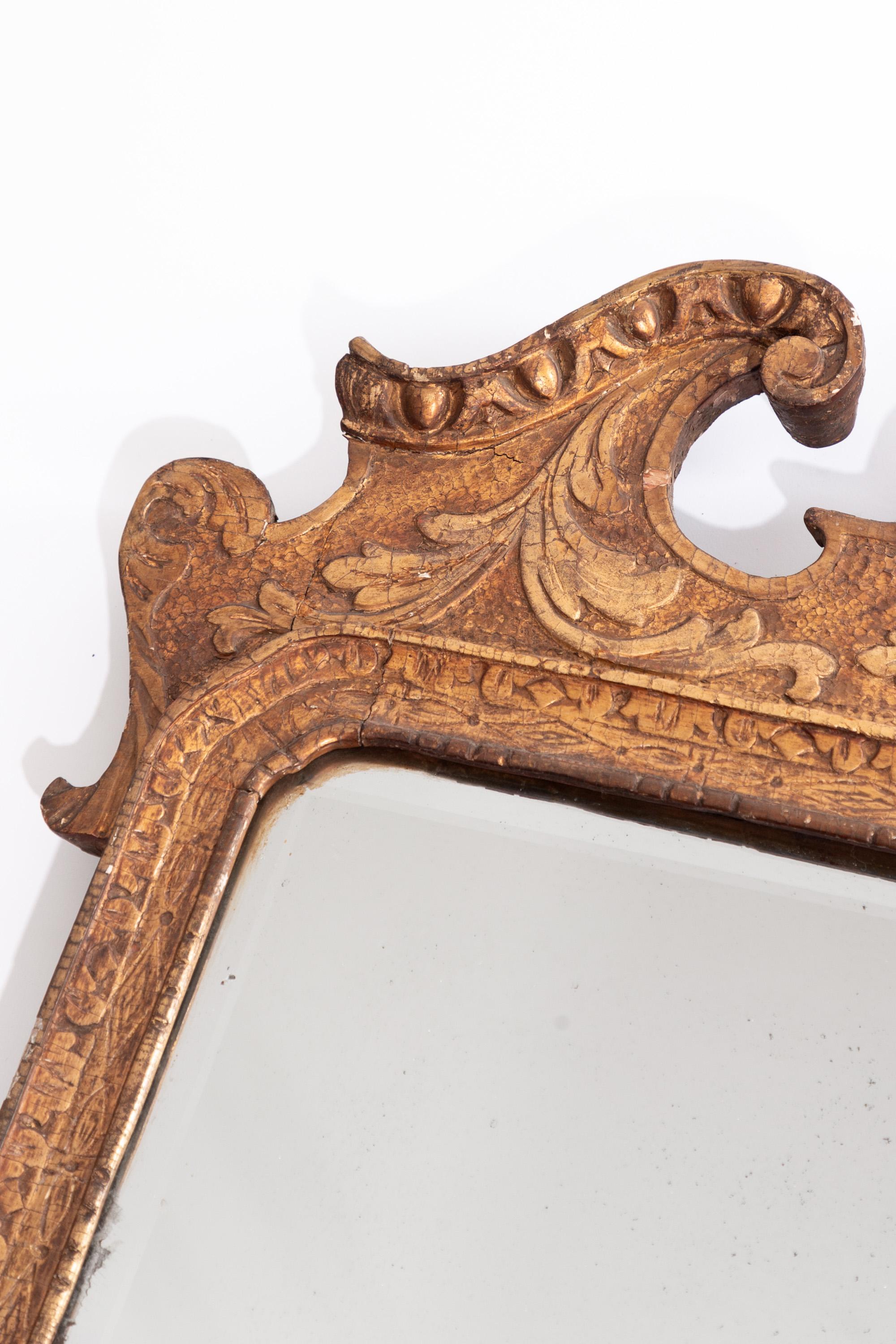 Specchio in legno dorato di Giorgio II, 1735 circa

Il piatto rettangolare smussato è incastonato all'interno di un bordo intagliato geometricamente, sormontato da un frontone spezzato intagliato ad acanto e centrato da un cartiglio foliato con