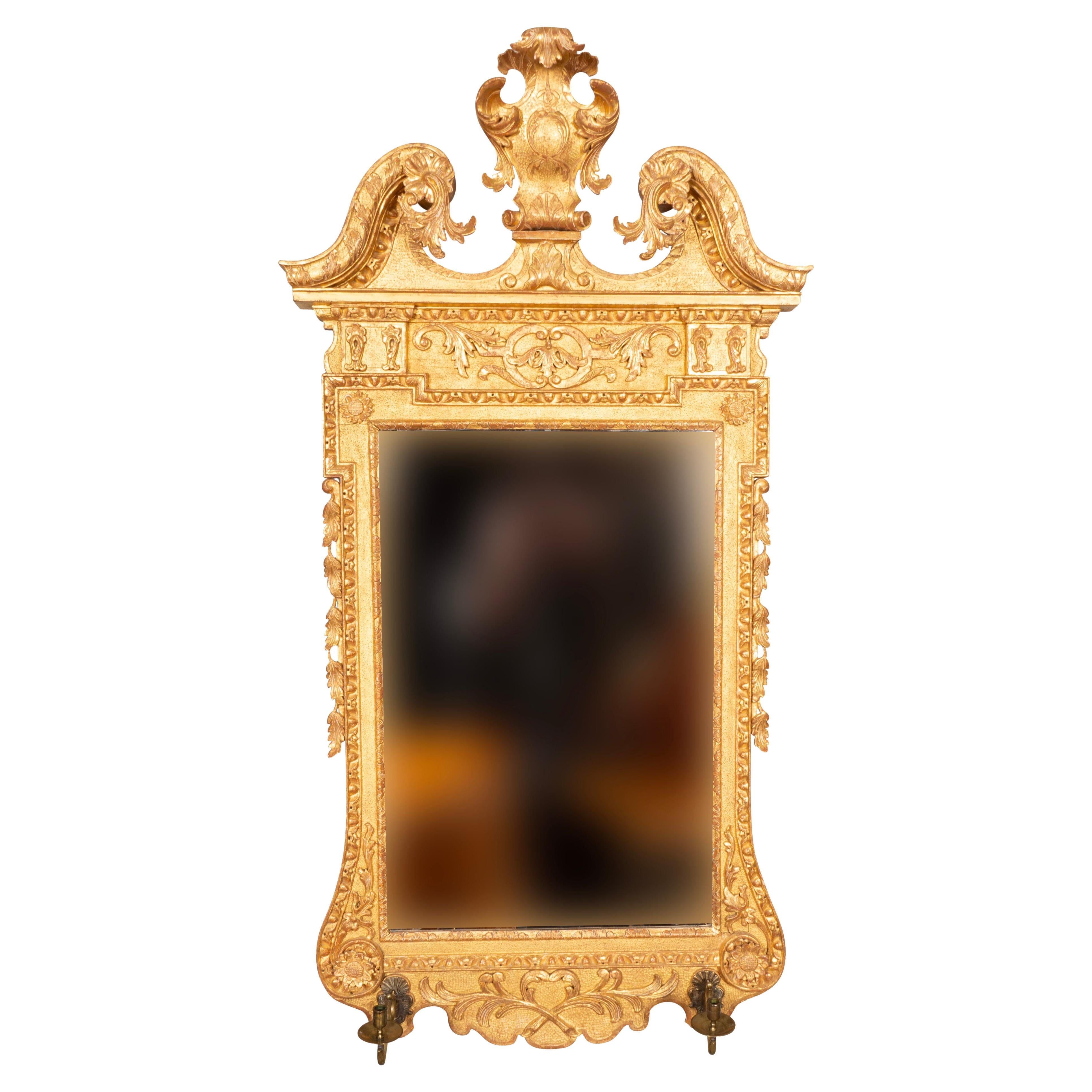 With swan neck pediment with central cartouche over a mirror plate and pair of detachable candle arms. The frame with egg and dart, leaf and flower decoration. Likely regilt ant some point but done correctly with burnished gold leaf and traces of