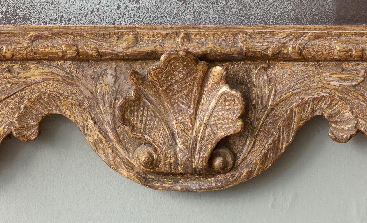 Specchio di Giorgio II in legno dorato con stemma di cherubino

Di forma insolita e caratteristica, con decorazioni foliate e creste di cherubini tra un frontone a collo di cigno spezzato, sopra un piatto smussato e due appliques in ottone