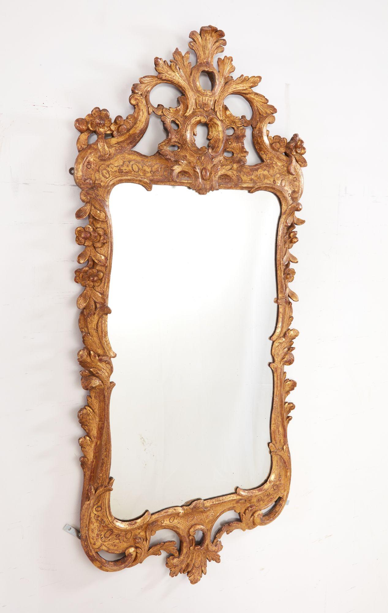 Feiner Spiegel aus vergoldetem Holz aus der Zeit von George II. mit Schnitzereien in Form von Blättern und Rocaille in hohem und niedrigem Relief, mit original vergoldeter Oberfläche und wahrscheinlich originaler Quecksilberglasplatte. Wunderschöne