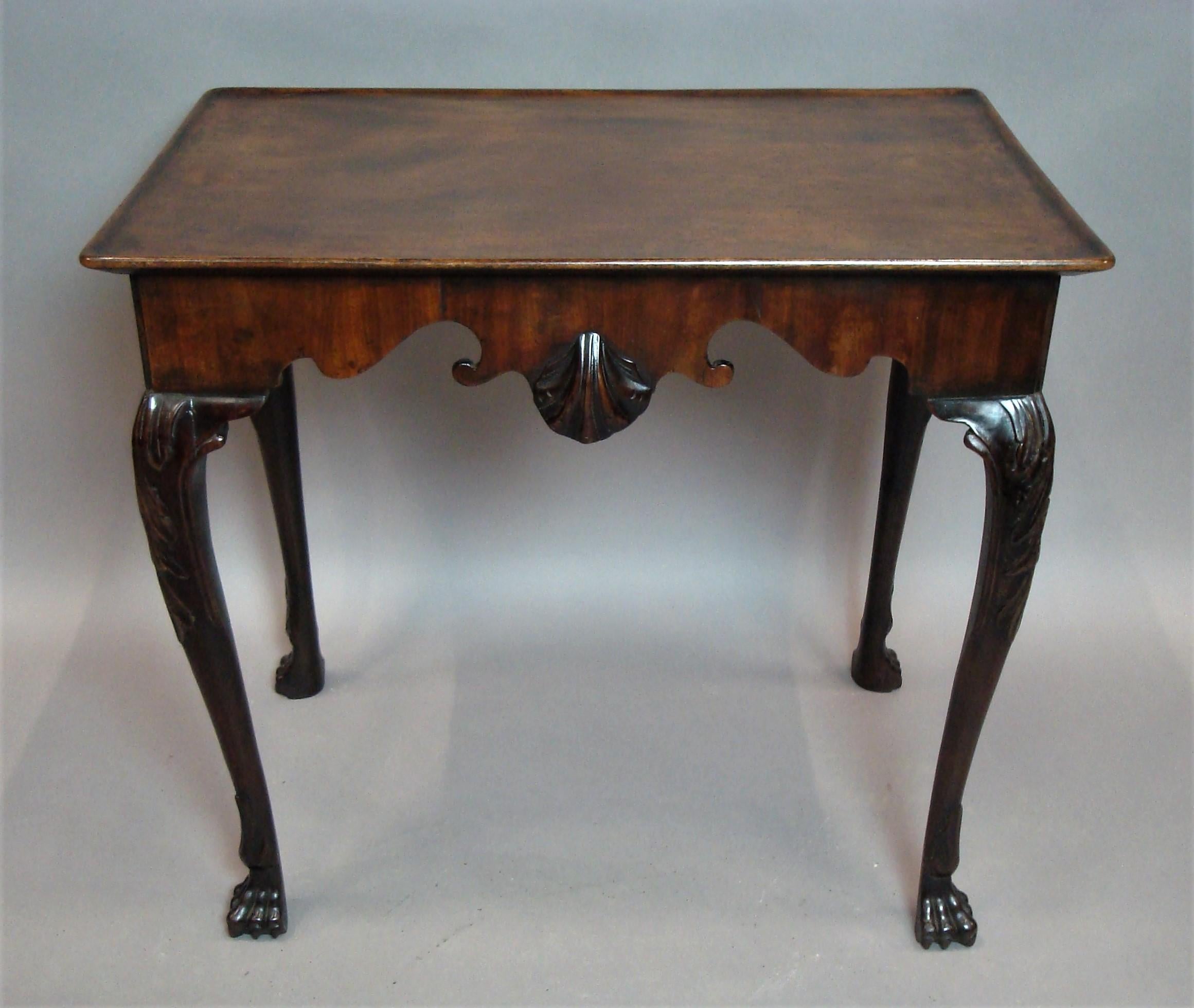 Good George II Irish mahogany silver table, the figured solid mahogany rectangular top with rounded corners and a lip moulded edge above a scrolled shaped frieze centred with a large carved scalloped shell; raised on acanthus carved cabriole legs