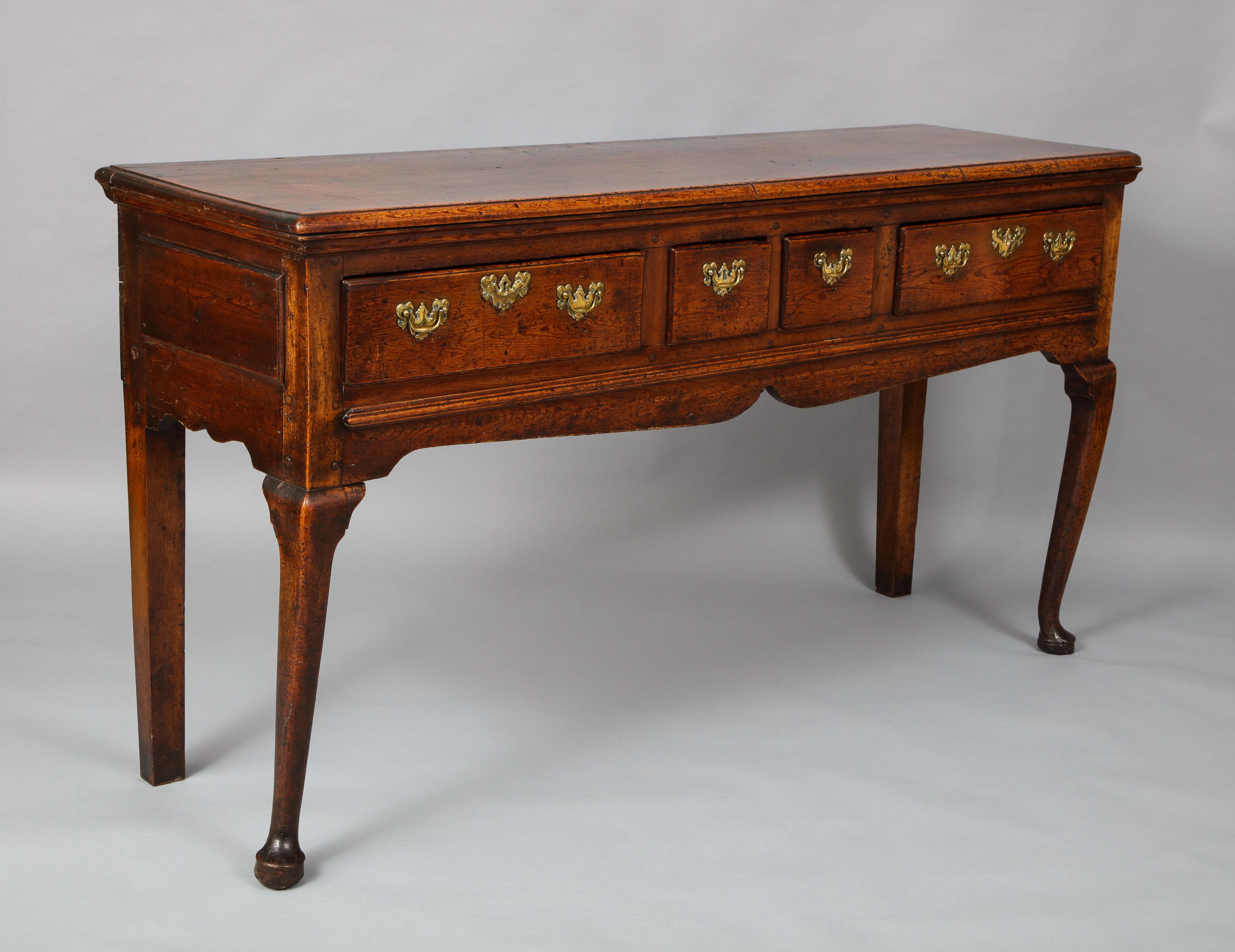 Very fine early 18th century English low dresser in richly patinated pine, the molded top over four drawers retaining original brass hardware, over cupid bow shaped apron and standing on cabriole front and square back legs, the whole with good rich,