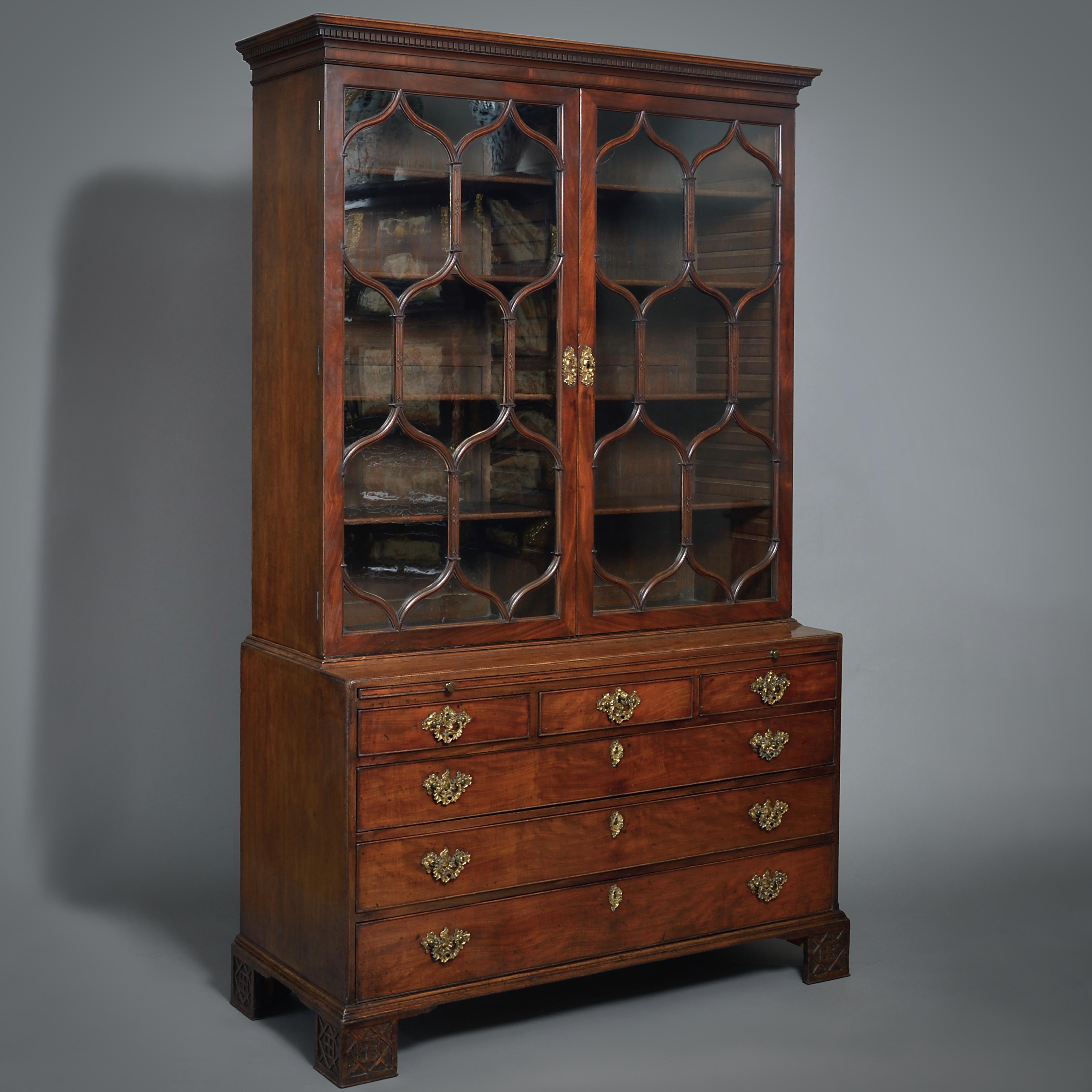 A FINE GEORGE II MAHOGANY BOOKCASE, CIRCA 1755.

Fitted throughout with it's original lacquered brass Rococo handles. The top retaining its original glass panes divided by ogee blind-fret carved glazing bars. The base with a baize-lined brushing