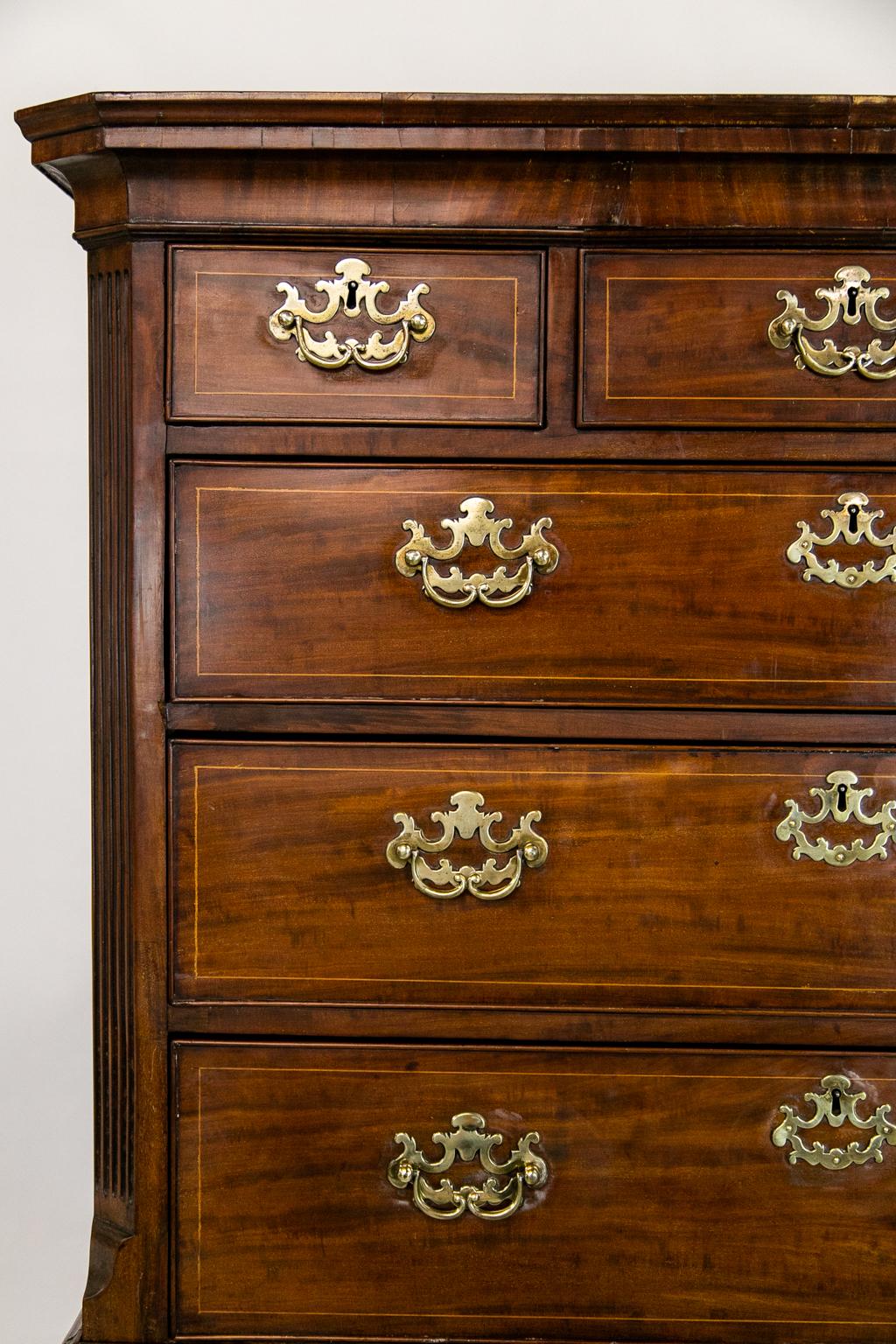 This George II mahogany chest on chest retains all of its original hardware, feet, and crown molding. The drawers have boxwood string inlay. The top has fluted chamfered corners that terminate in a lamb's tongue.
  