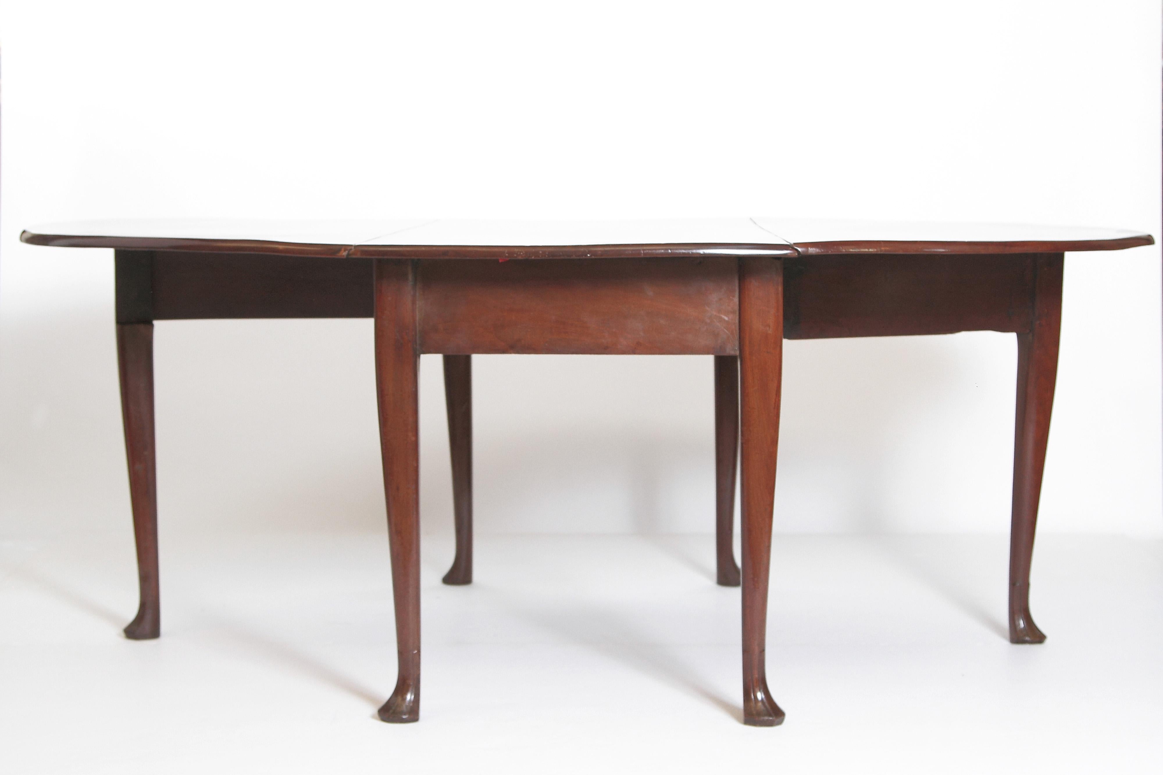 George II drop-leaf dining table in a beautifully grained mahogany with the legs terminating in Spanish feet. Measurements with leaves down: 61.5 D x 27 W x 29.5 H.