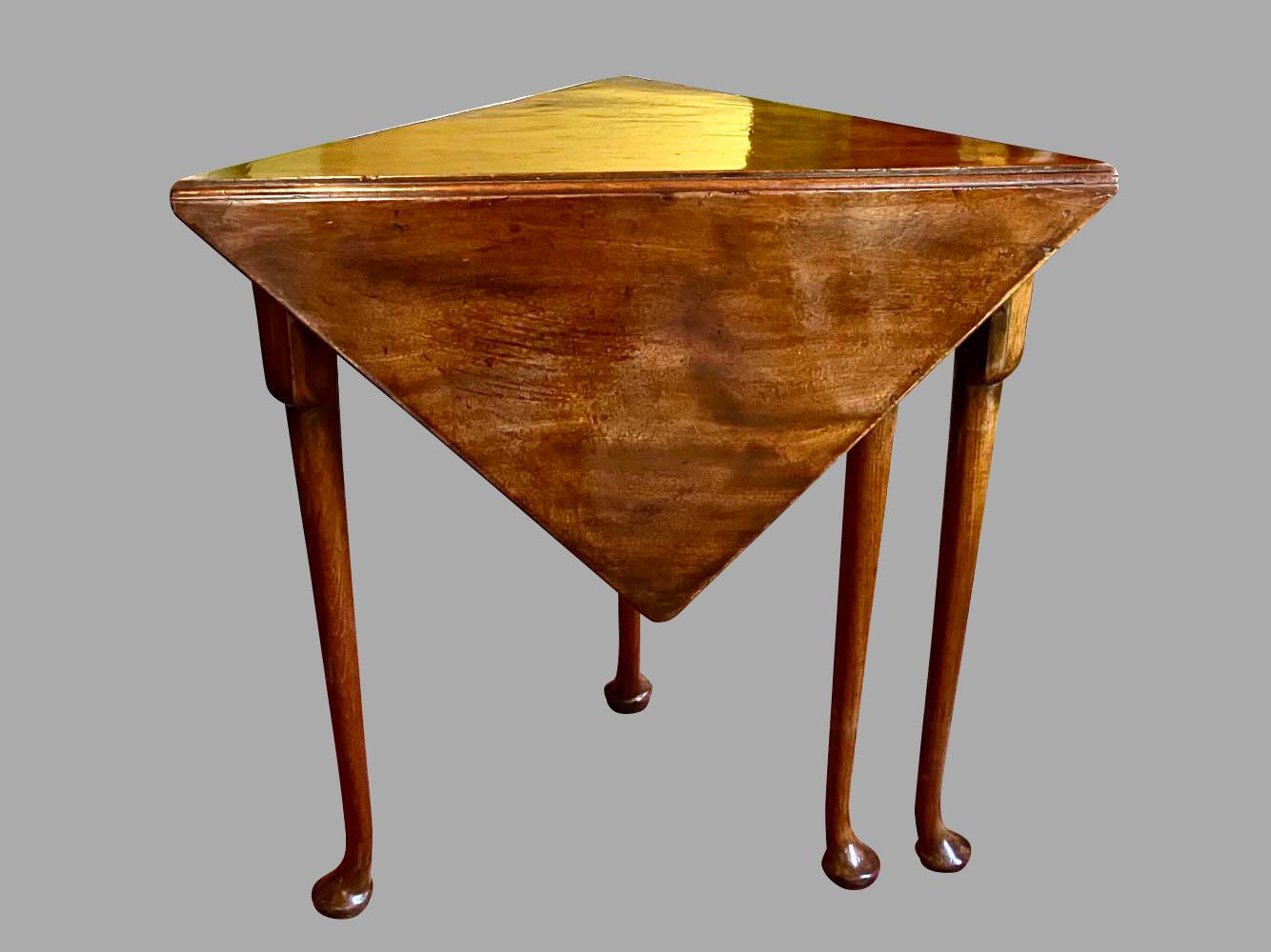 A pretty English mahogany corner or envelope table, the fold down top above a plain frieze resting on shaped legs ending in pad feet. When opened, with the swing leg in position, the top measures 21