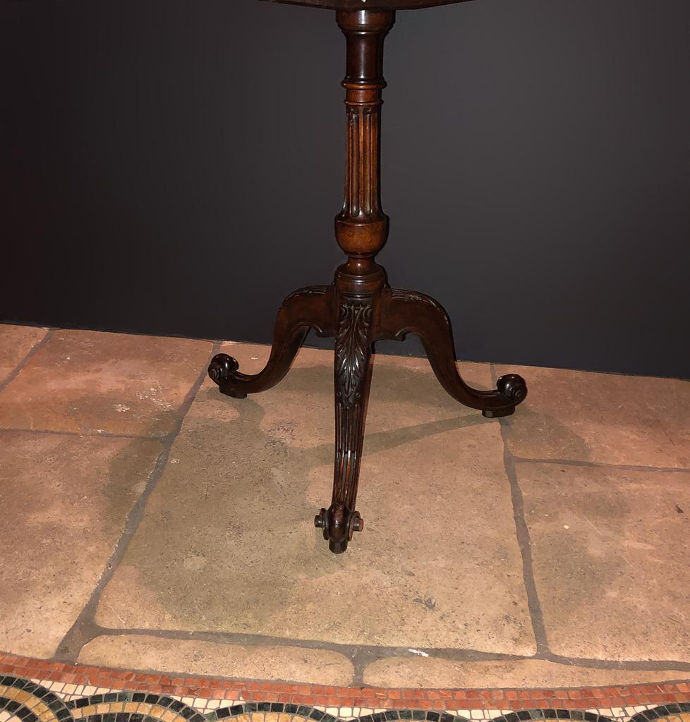 A fine George II mahogany carved pie crust table with an urn form fluted column support, acanthus carved cabriole legs on boldly carved scroll feet.