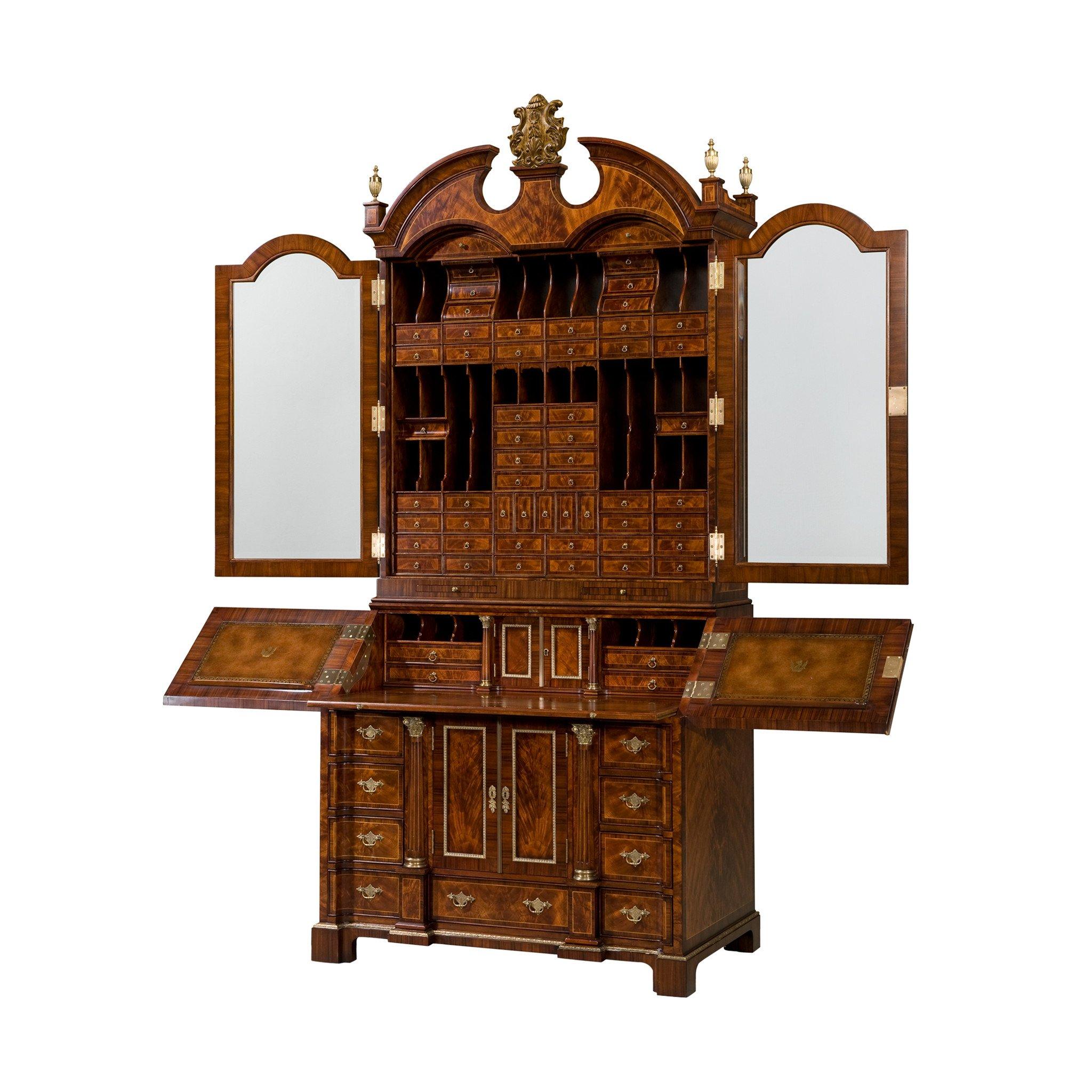 A flame mahogany and rosewood banded Bureau cabinet, with an architectural cornice centred by a gilt crest, above two glazed doors enclosing 45 drawers and 19 pigeon holes above two slides, the bureau opening to reveal a leather inset slide and a
