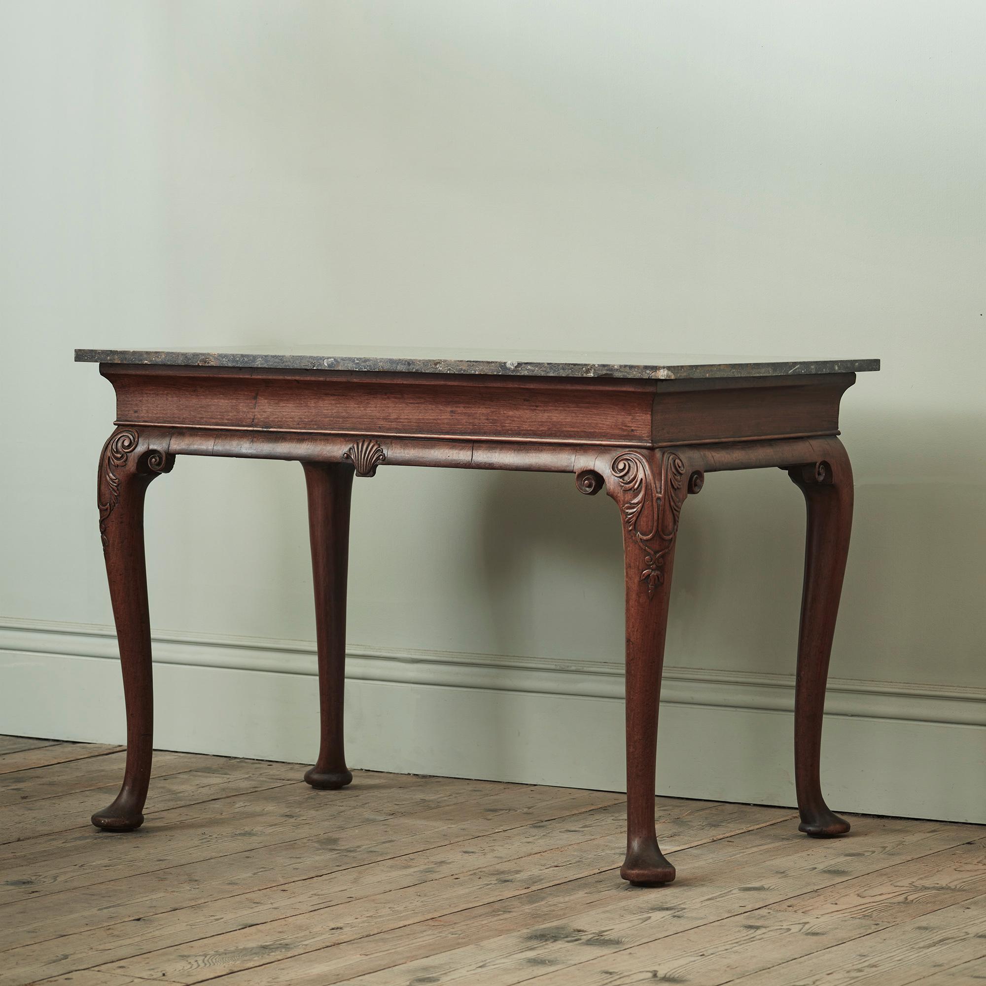 A George II Mahogany Side Table, with Highly Figured “Fossil Brown” Marble Top

Of quite and humble form, with plain shaped frieze above an apron incorporating a modestly scaled central carved scallop shell, with carved acanthus cabriole leg on pad