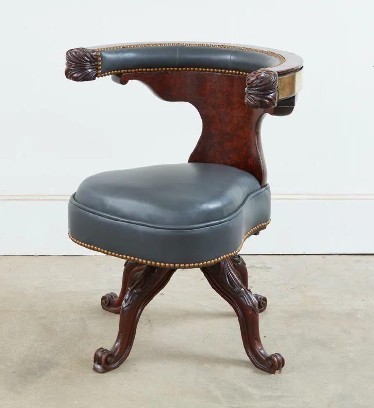 An unusual and rare mahogany swivel reading chair with a show wood back rail upholstered on the front side to allow for use to both sit in to use as a desk chair as well as to straddle for reading, having extraordinary and boldly carved acanthus