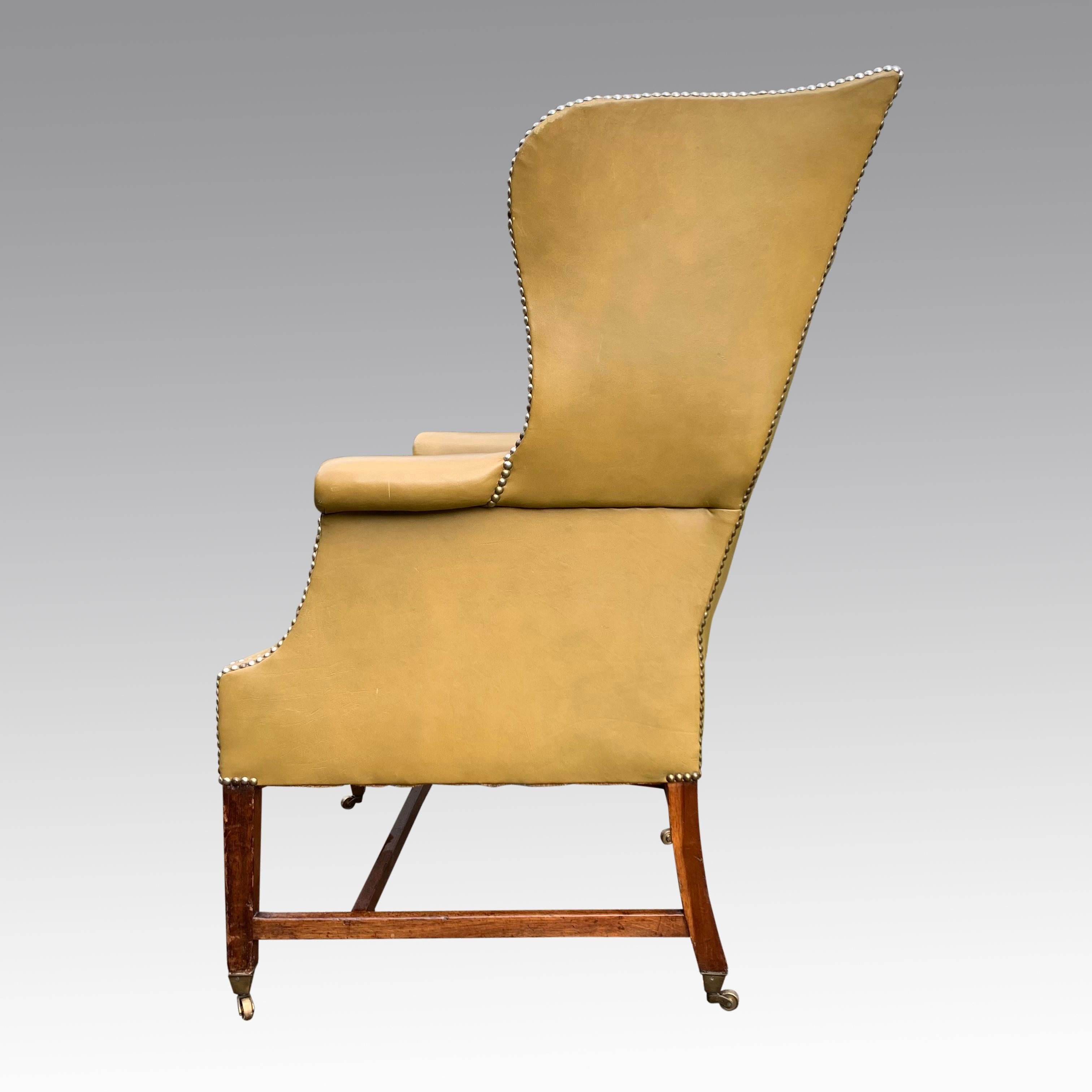 A good George III period mahognay wing armchair covered in a pale green leather which is nicely aged and mellowed. The chair of classical shape with pleasing design, standing on square tapering legs with brass cups and castors and 'H' stretchers