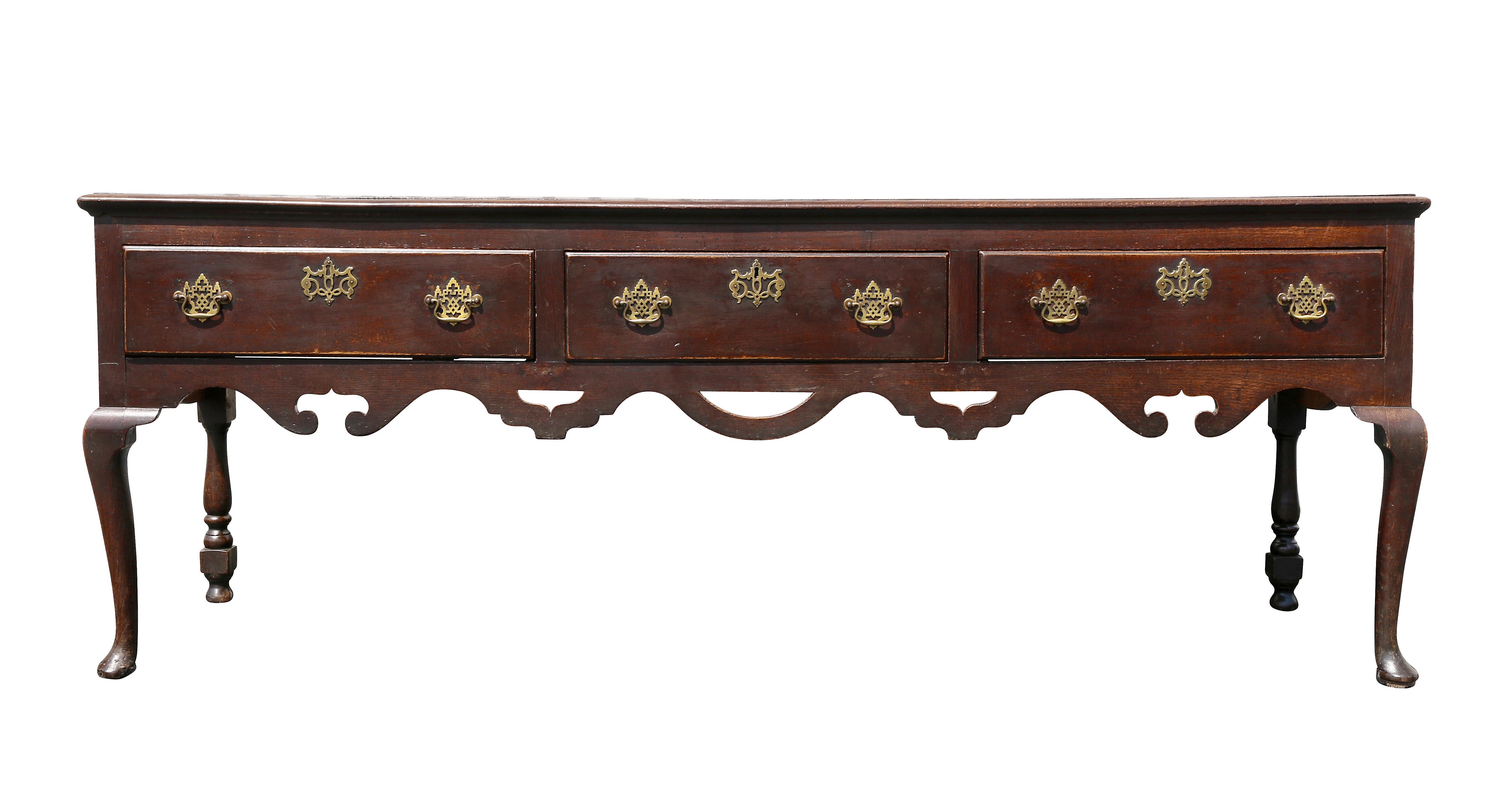 Rectangular top over three drawers and a carved open work apron, raised on cabriole legs. Rear legs are turned. Brass handles.