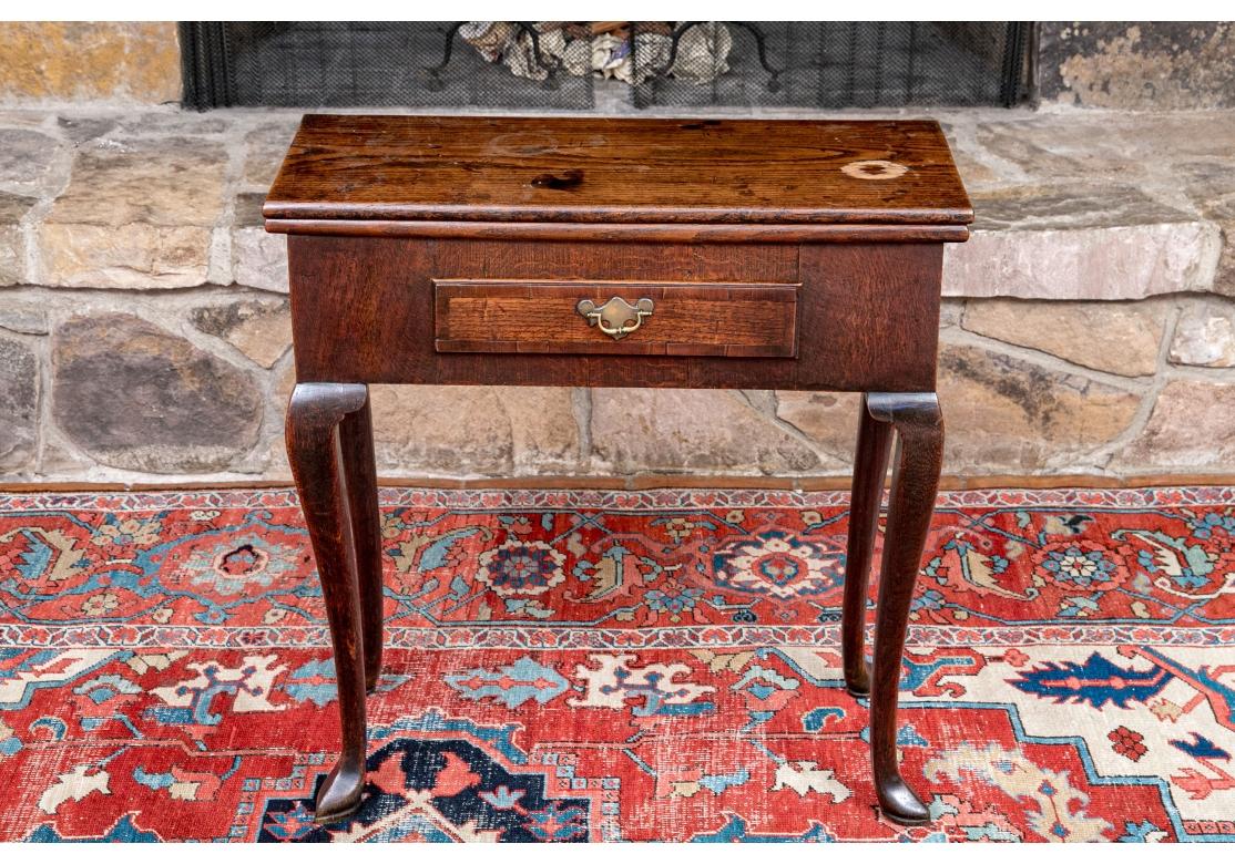 George II oak games table with hand-cut dovetail joinery, single drawer with brass drop pull and resting on cabriole legs including a gate leg with pointed and padded feet.

Dimensions: 29 