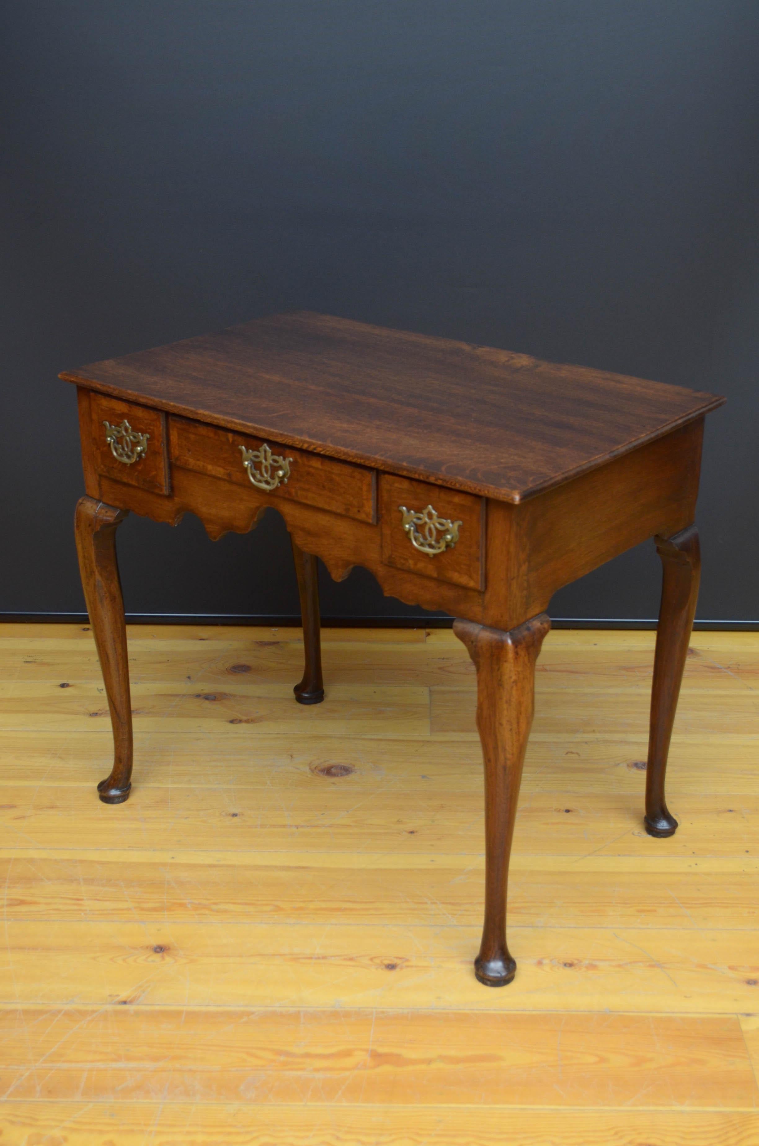 Sn5411 Georgian, oak side table, having oversailing top above three frieze oak lined drawers with crossbanded edge and fitted with original handles, all standing on cabriole legs terminating in pad feet. This antique table retains its original