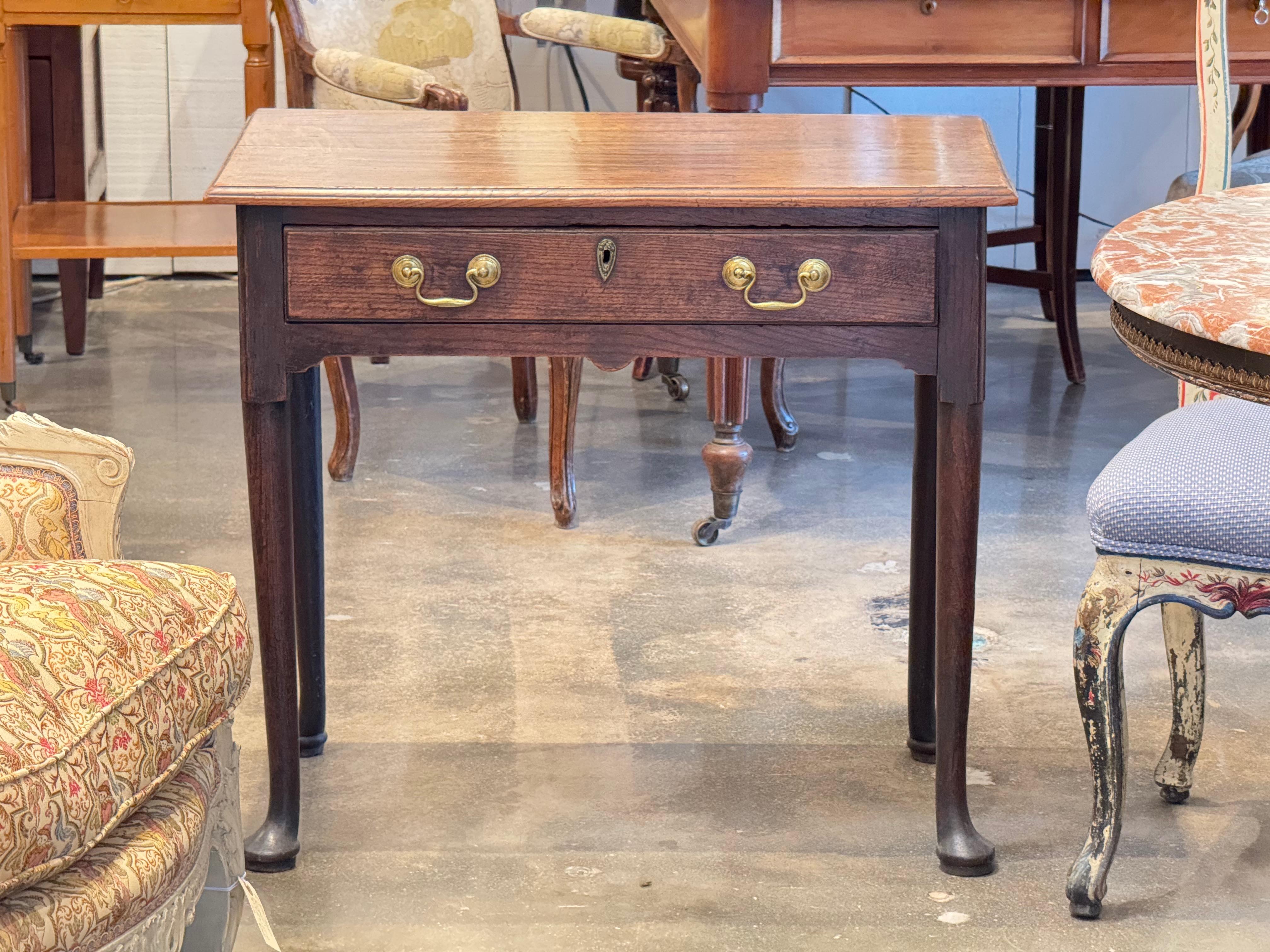 Table d'appoint anglaise du XVIIIe siècle de style George II en chêne massif à la patine riche et chaude. Le plateau rectangulaire repose sur un tiroir unique avec des poignées en laiton et un écusson d'origine. Les pieds cabriole se terminant par