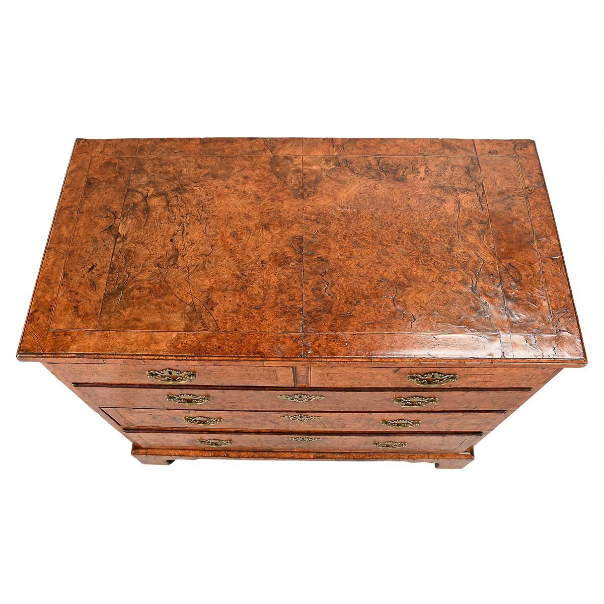 A George II period chest of drawers veneered in burr elm with contrasting line inlay to the top and drawer fronts. The greater part of the top is done with two book-matched pieces of veneer. The oak-lined drawers are configured as two short drawers