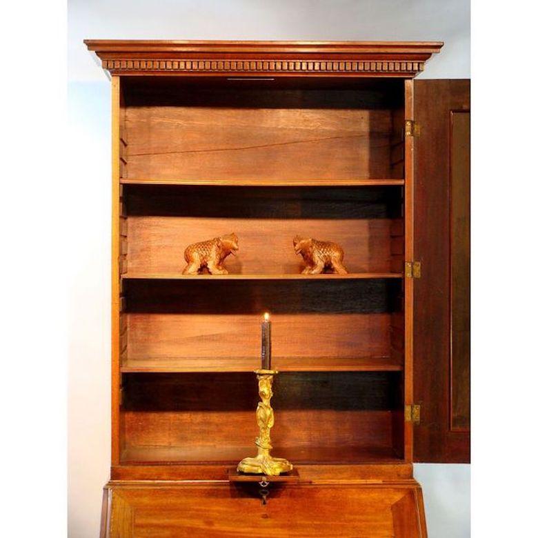 A rare and elegant small George II period mahogany bureau bookcase. 

The top section with a bold dentil cornice, consisting of a single moulded door with later mirror plate, re-entrant corners and with a pull-out candle slide. The interior with