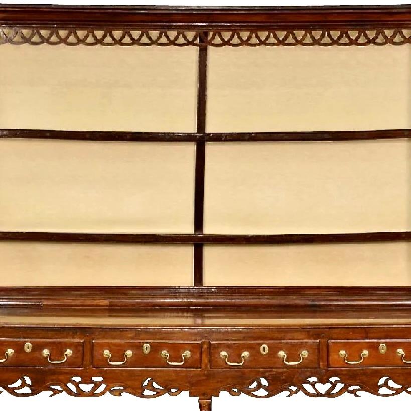 A fine and decorative Welsh dresser, dating probably ca. 1740-1760, with a pierced and carved frieze as well as an especially interesting interlaced carved apron over an open baluster front base. Welsh dressers were important case pieces built to