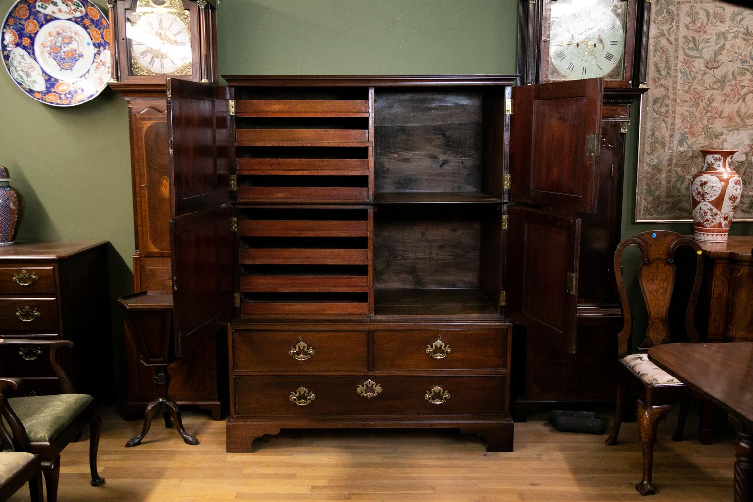This rare George II press cupboard has open cupboards behind the two right hand doors and four pull out trays in both left upper and left lower doors. The door retains its original working lock and key. The drawer handles are original. There are