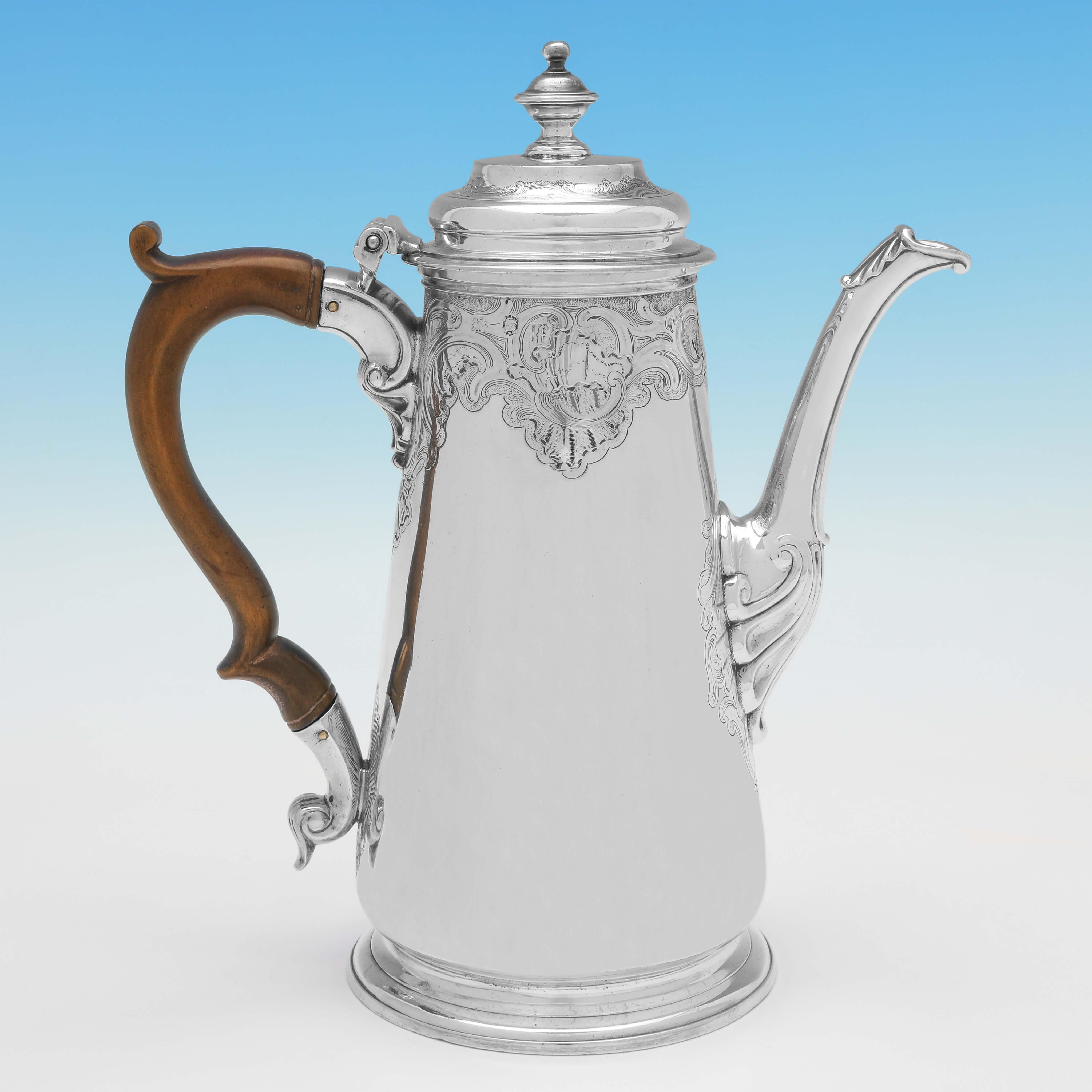 Hallmarked in London in 1741 by Gabriel Sleath, this striking, George II, Antique Sterling Silver Coffee Pot, features flat chased decoration below the rim, an engraved armorial to one side, and a wooden handle. 

The coffee pot measures 9