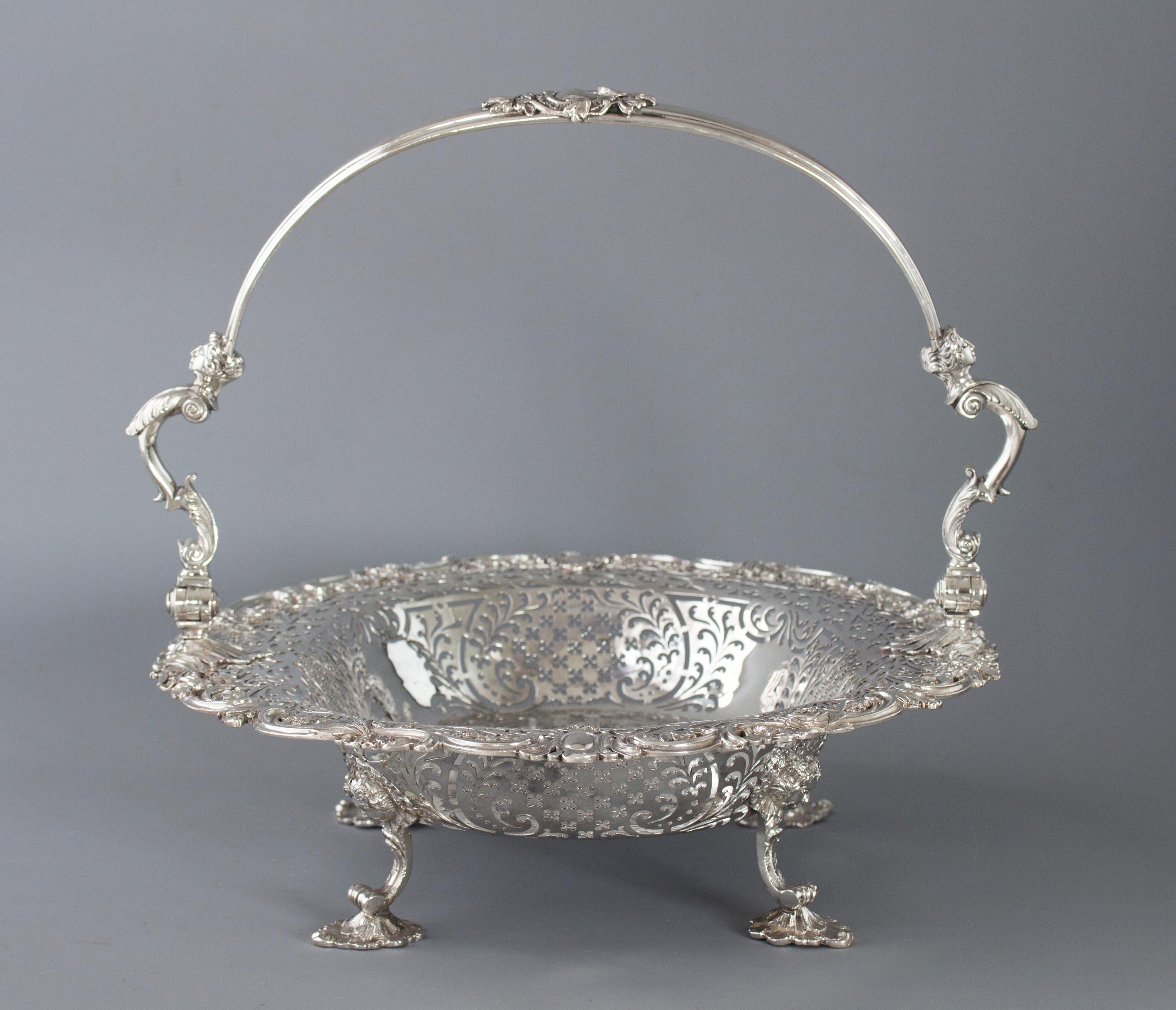 A very good large silver swing handle basket of pierced oval form. The arched swing handle with two cast female busts arising from a leaf capped double C-scroll support. The cast and applied rim of shaped foliate and floral entwined decoration. The