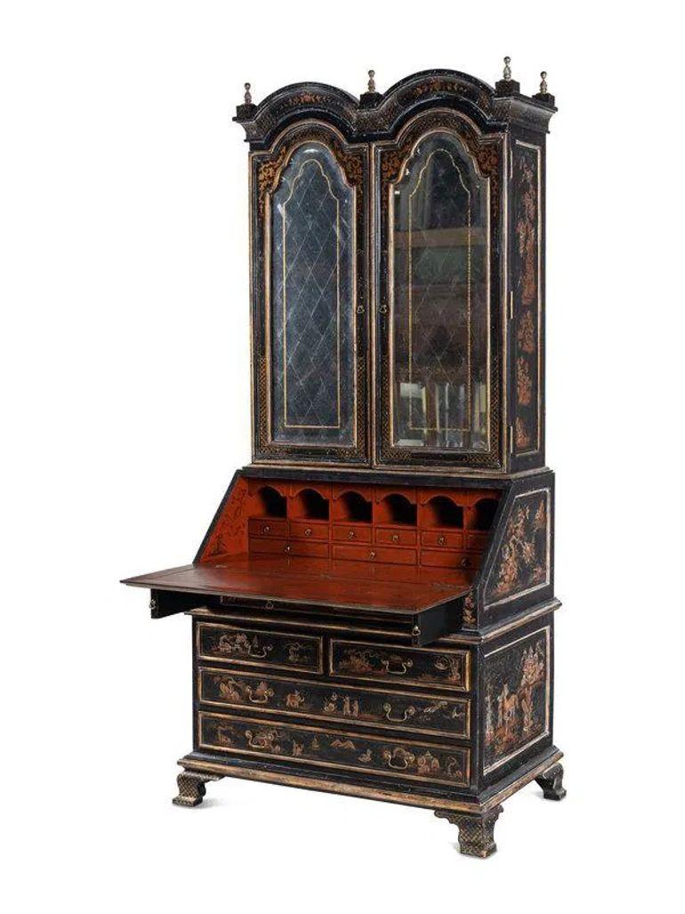 Élégante bibliothèque-bureau anglaise du début du XXe siècle de style George II, présentant un décor noir et japanné doré avec des motifs inspirés de la chinoiserie. La partie supérieure présente un fronton mouluré au-dessus d'une paire de portes