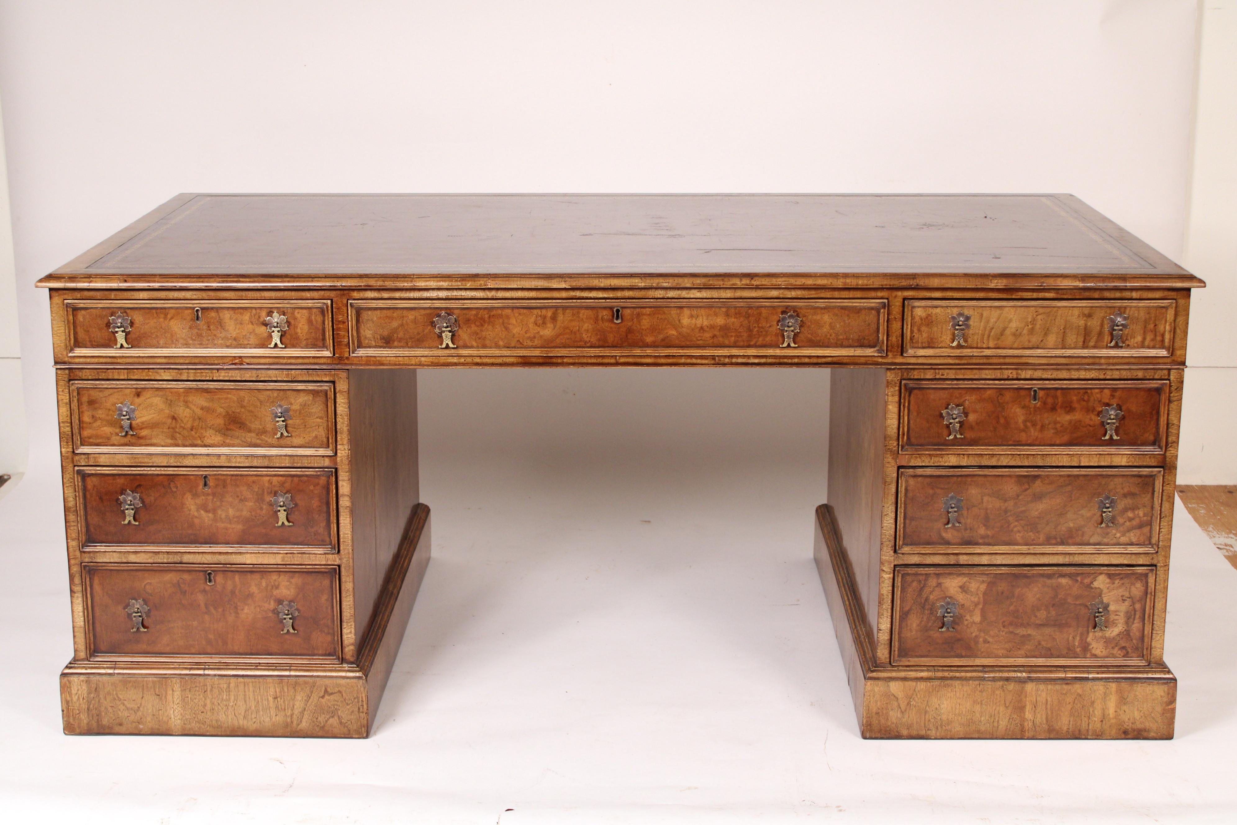 George II style burl walnut double pedestal partners desk with a tooled leather top, made by Burton Chang, circa late 20th century. With a red tooled leather overhanging top, 3 burl walnut frieze drawers on front and back sides, two burl walnut