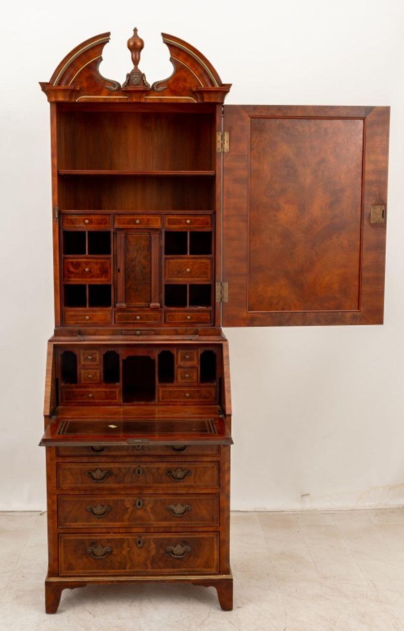 Gabinete de nogal y nogal Burr estilo Jorge II, por John Widdicomb, finales del siglo XX, con cabeza de león y monturas metálicas en capiteles de columnas, la mitad superior con puerta de espejo que da a dos estantes sobre ocho cajones y ocho