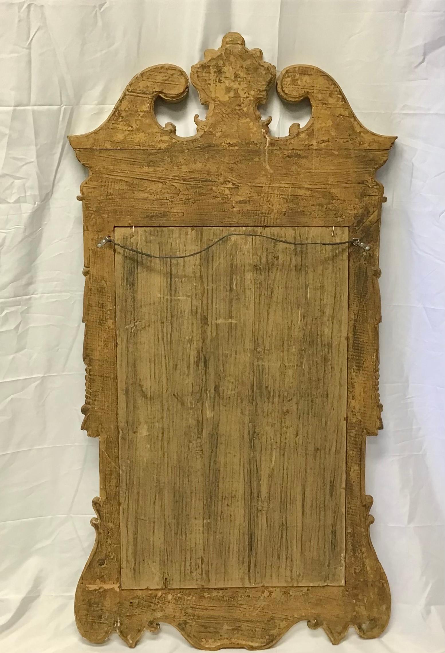 A fabulous Georgian style carved giltwood wall mirror dating from the mid 20th century with decoration typical of Georgian period. This antique mirror is exquisitely carved with scrolls, acanthus leaves, swags and shell and a distinctive pediment
